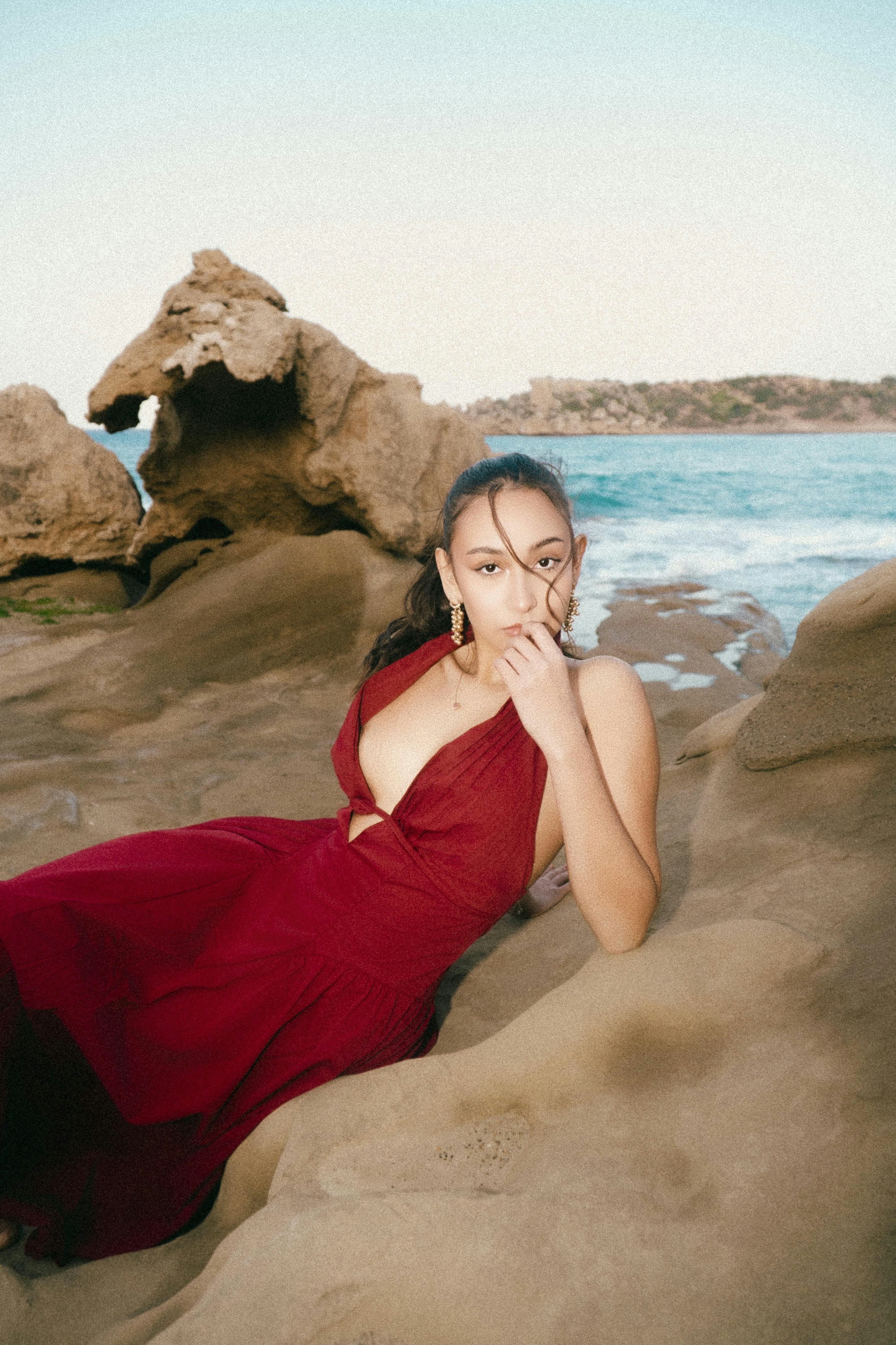 Woman in red dress reclining on coastal rocks