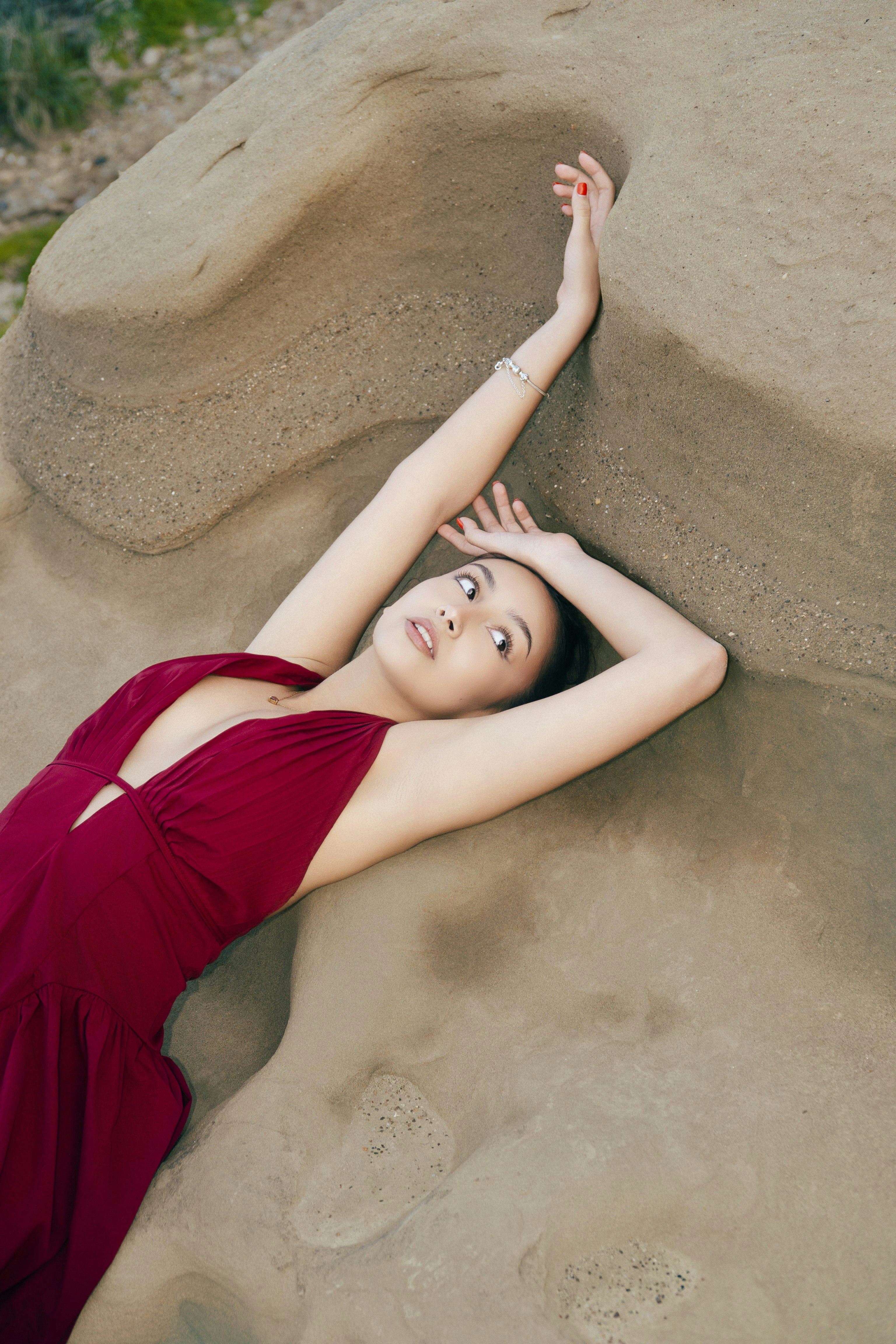 Woman in red dress posing on sculpted rock