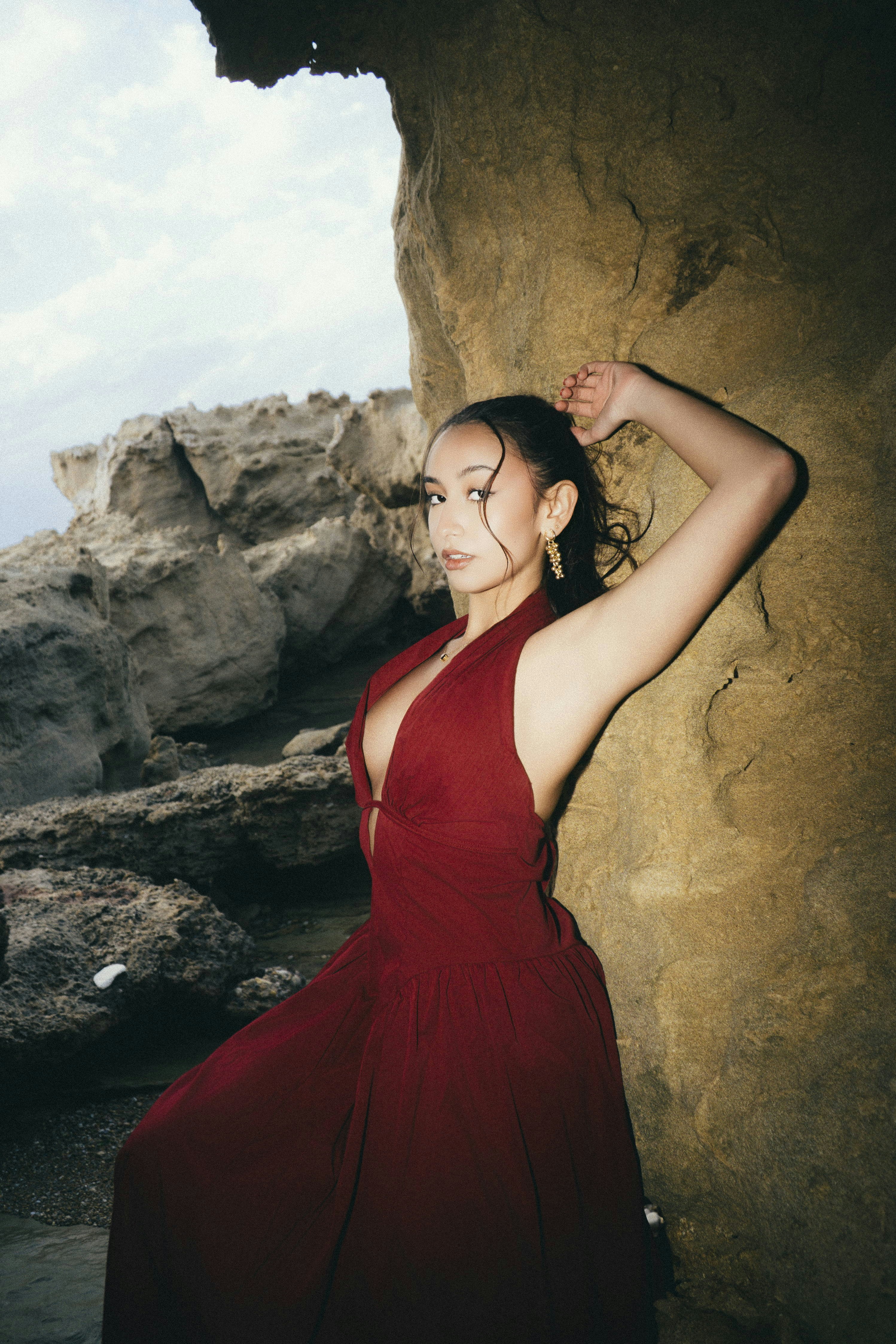 Woman in red dress posing among coastal rock formations