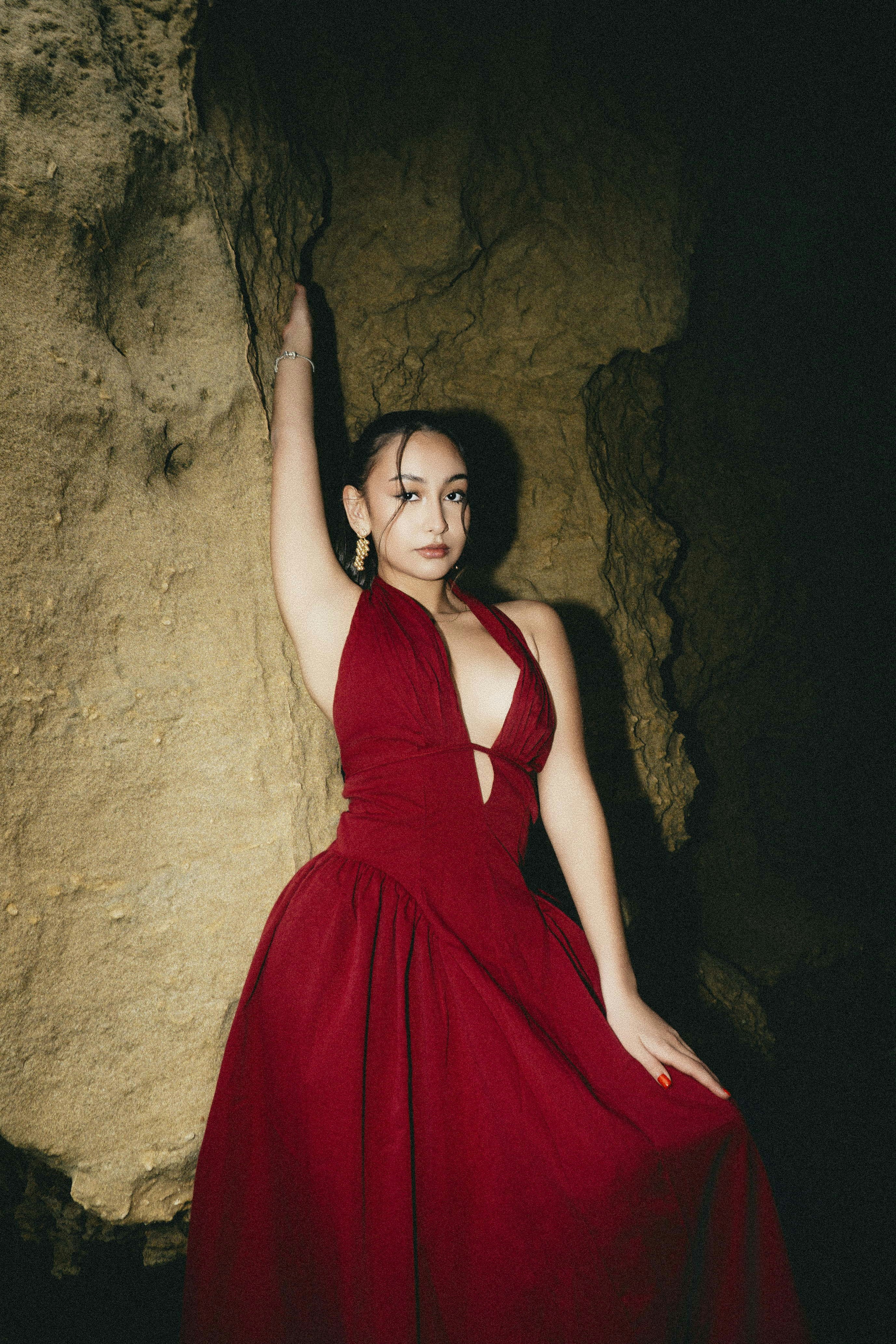 Woman in red dress posing inside a dark cave