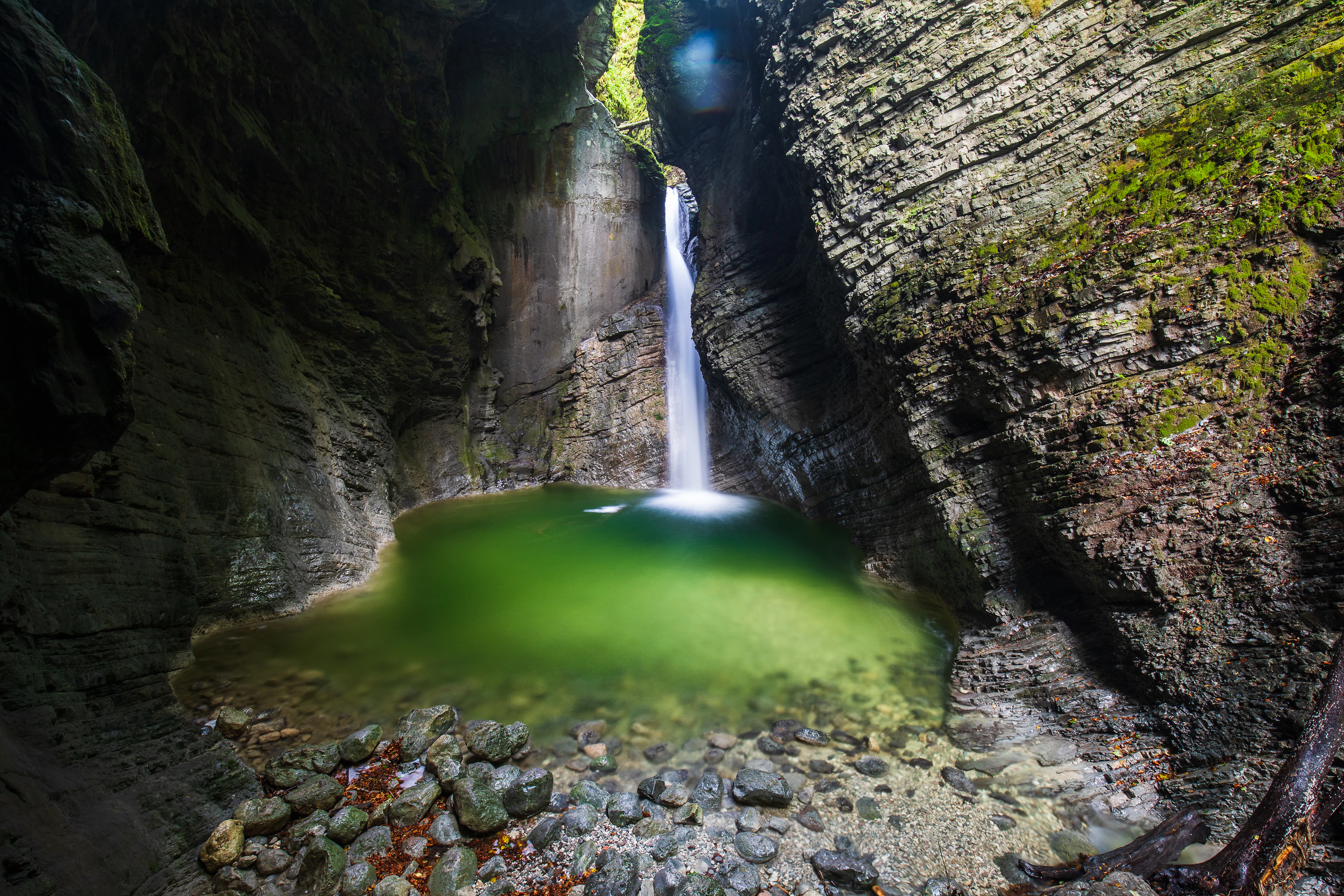 The Kozjak waterfall dropping into a green pool between dark limestone walls near Kobarid
