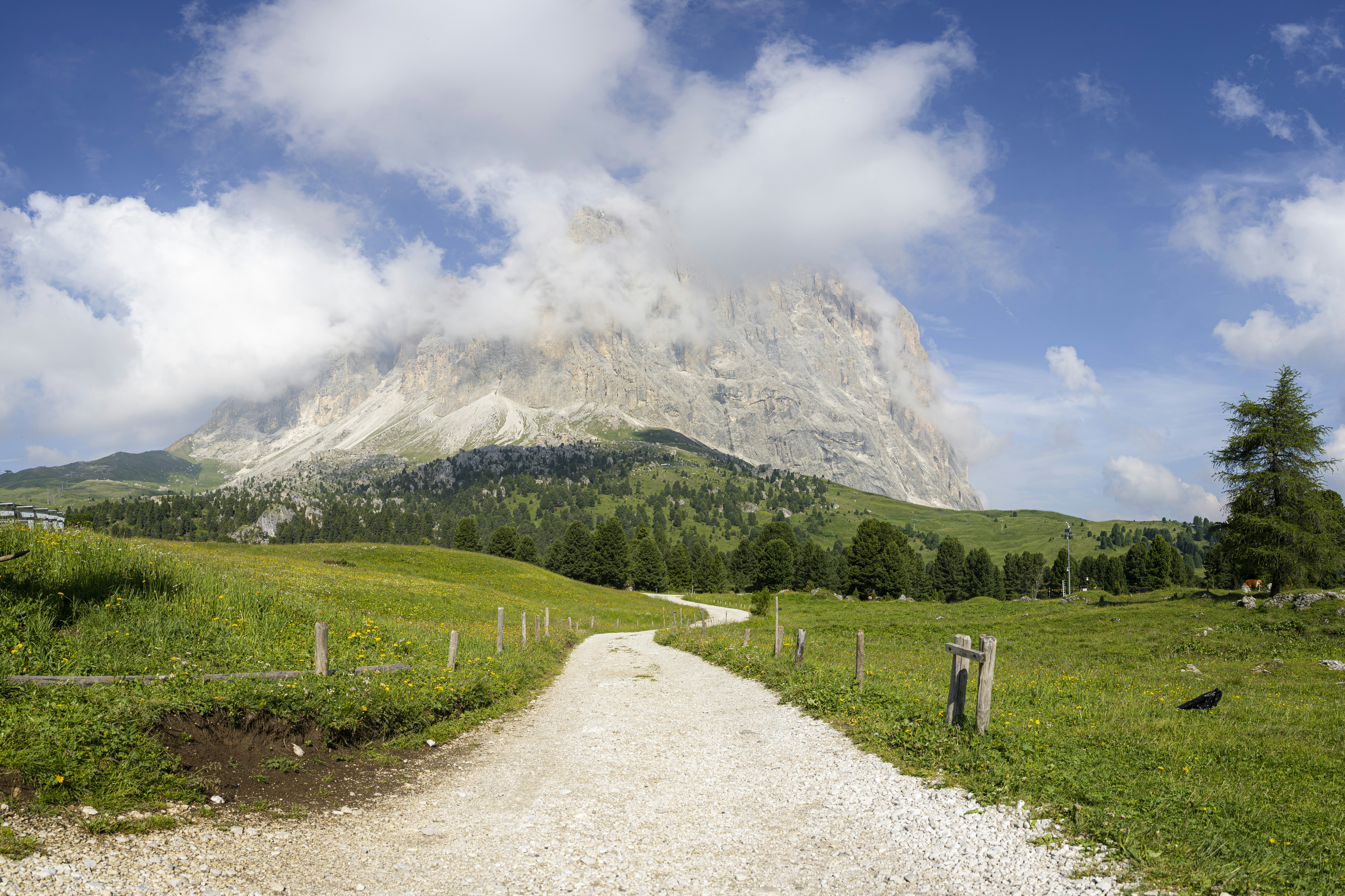 Green fields and a path beneath a cloud-covered mountain