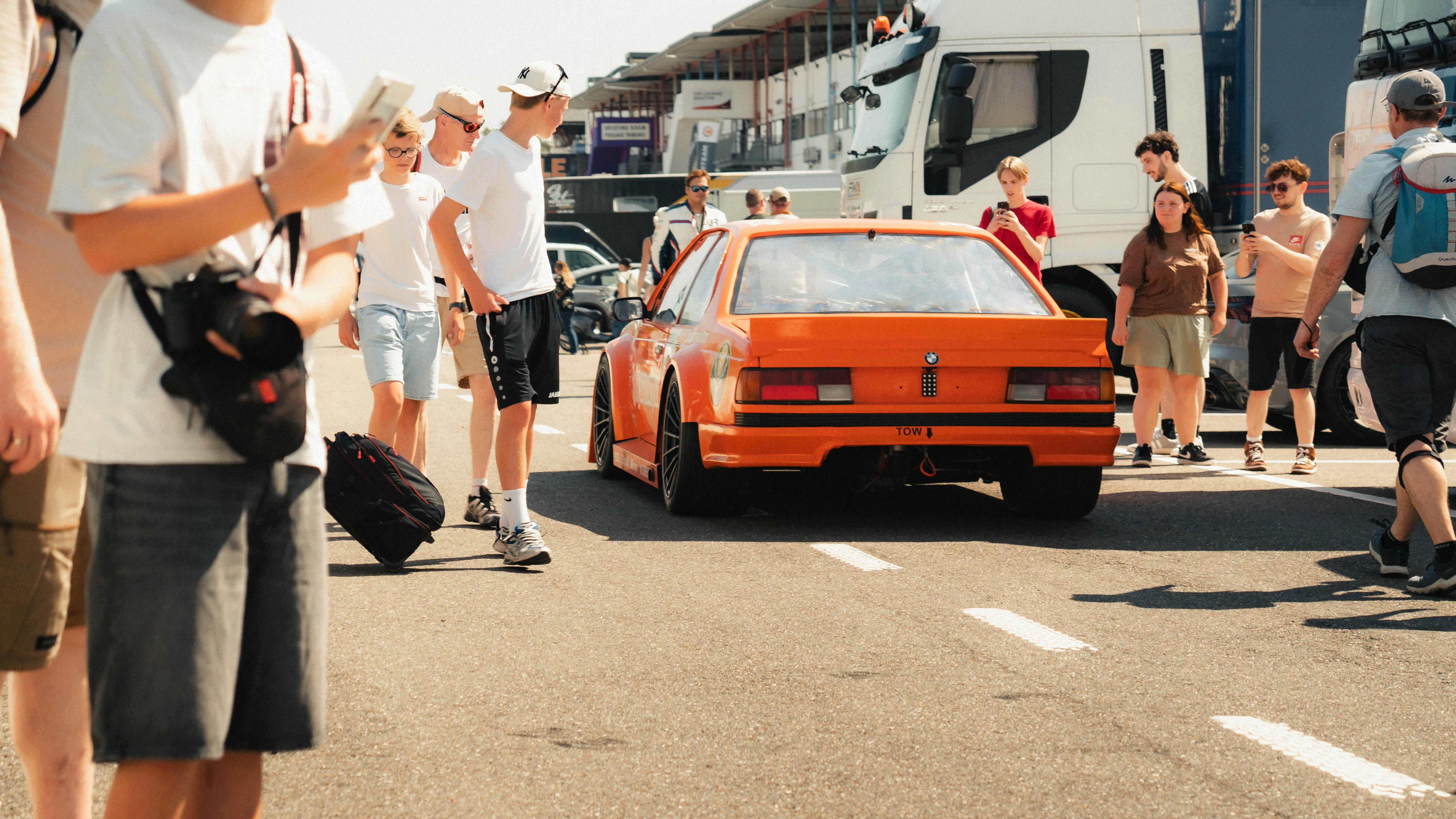 Cars Spectators Stand Around An Orange Car At A Sunny Event. 4K Wallpaper #3508
