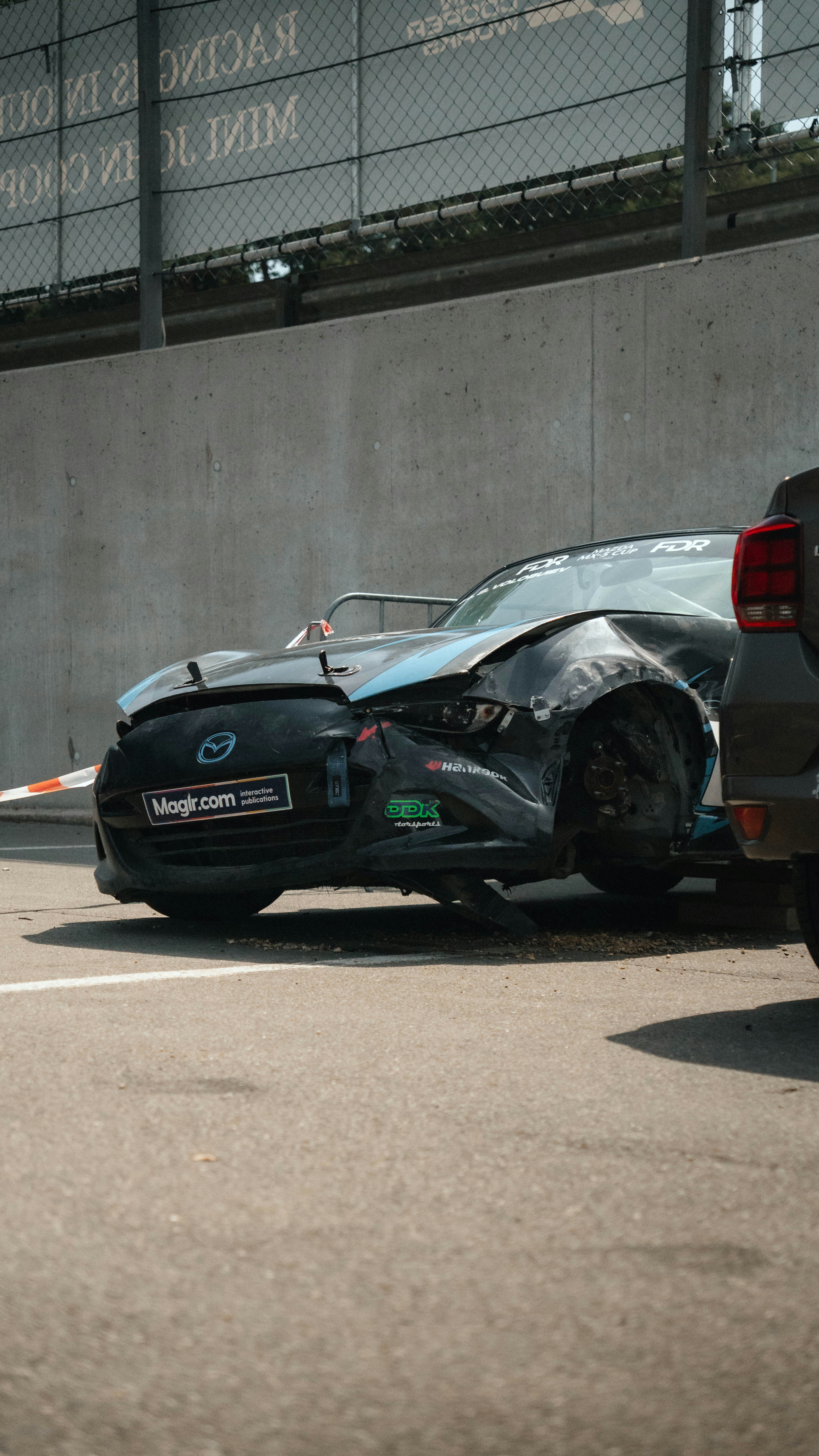 Heavily damaged race car with crumpled front on a track.