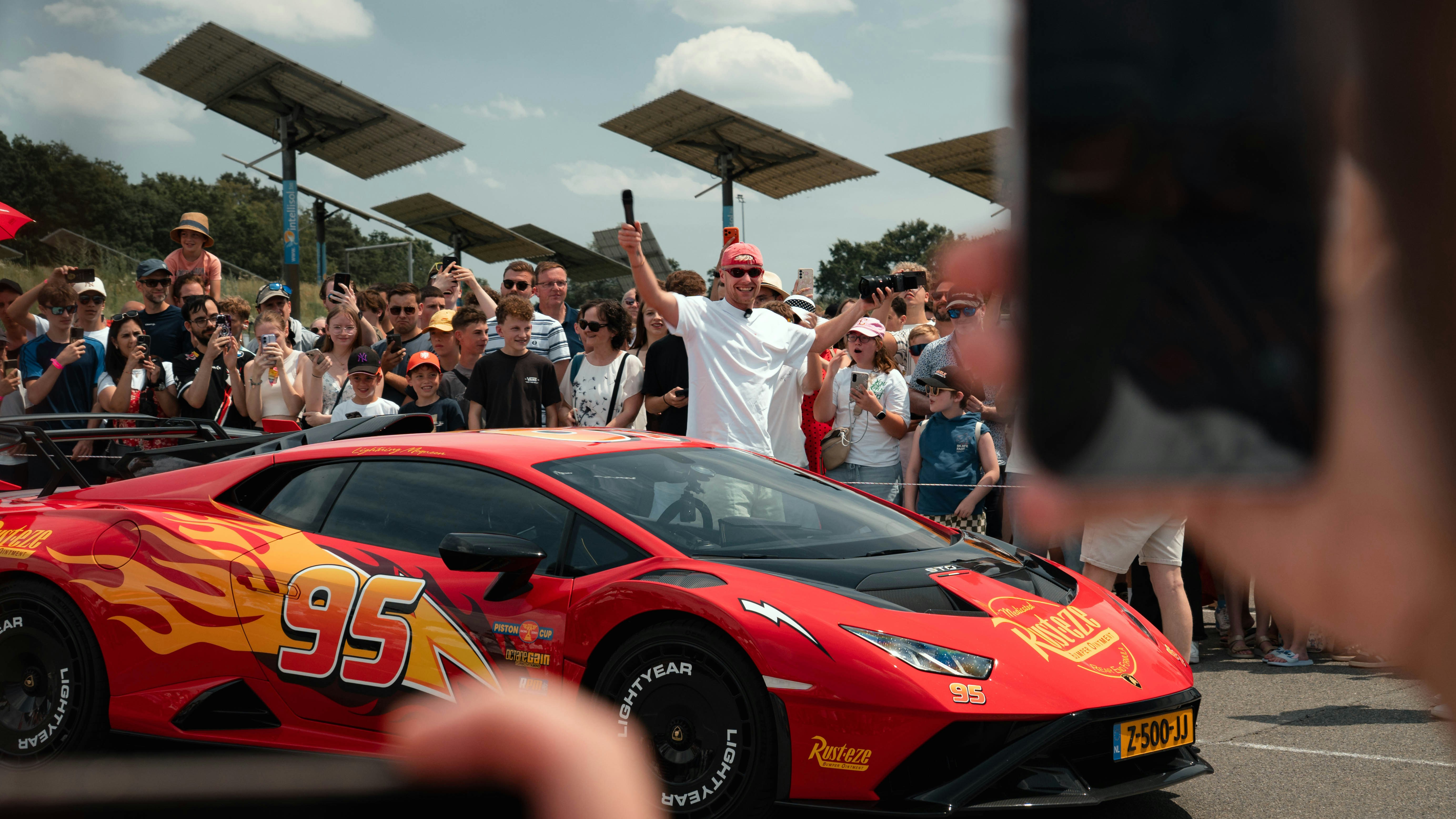 Cars Crowd Watches Man Celebrate On A Red Flame Decorated Sports Car. 4K Wallpaper #3507