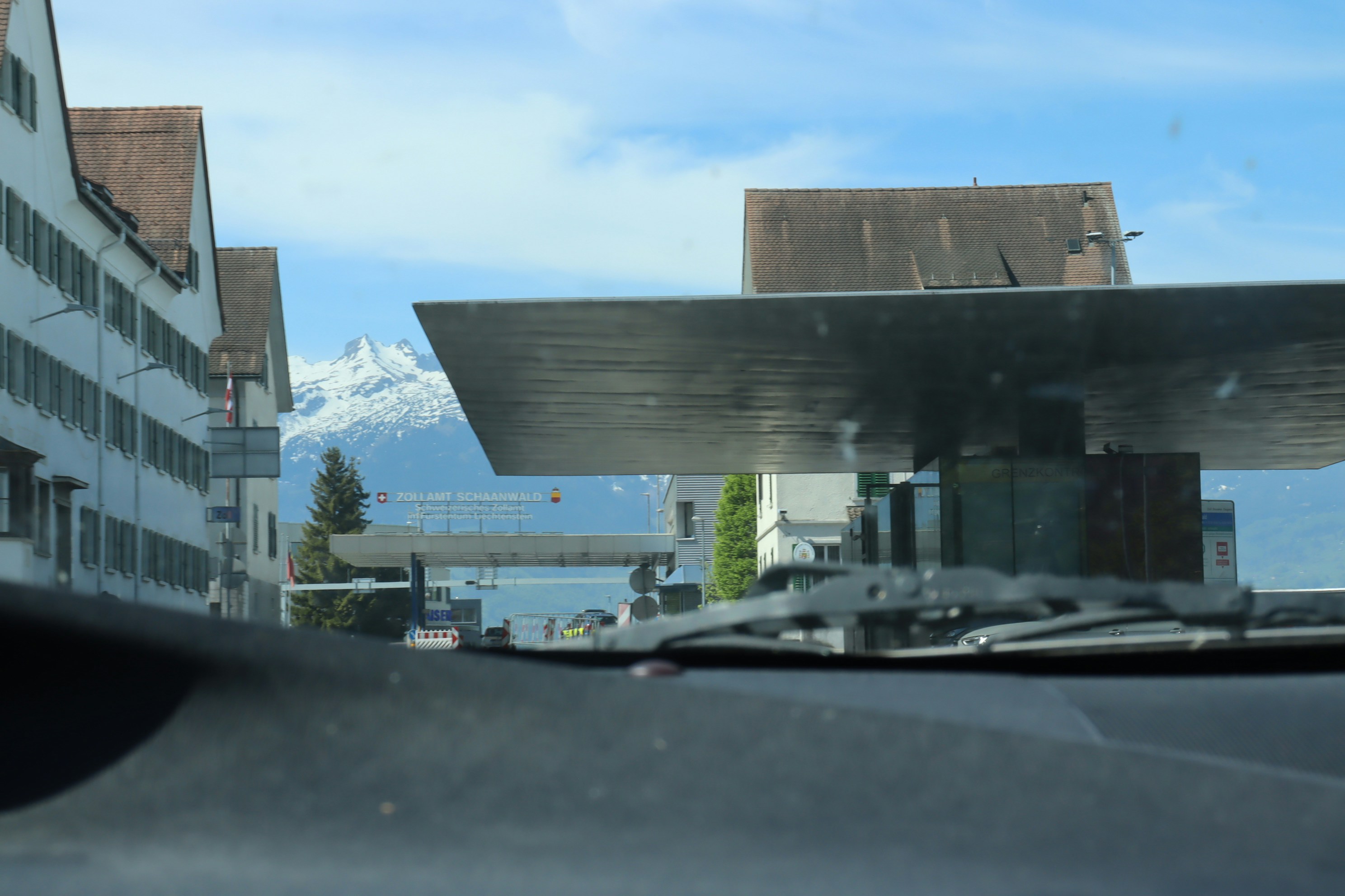 Dashboard view of buildings, modern structure, and distant mountain.