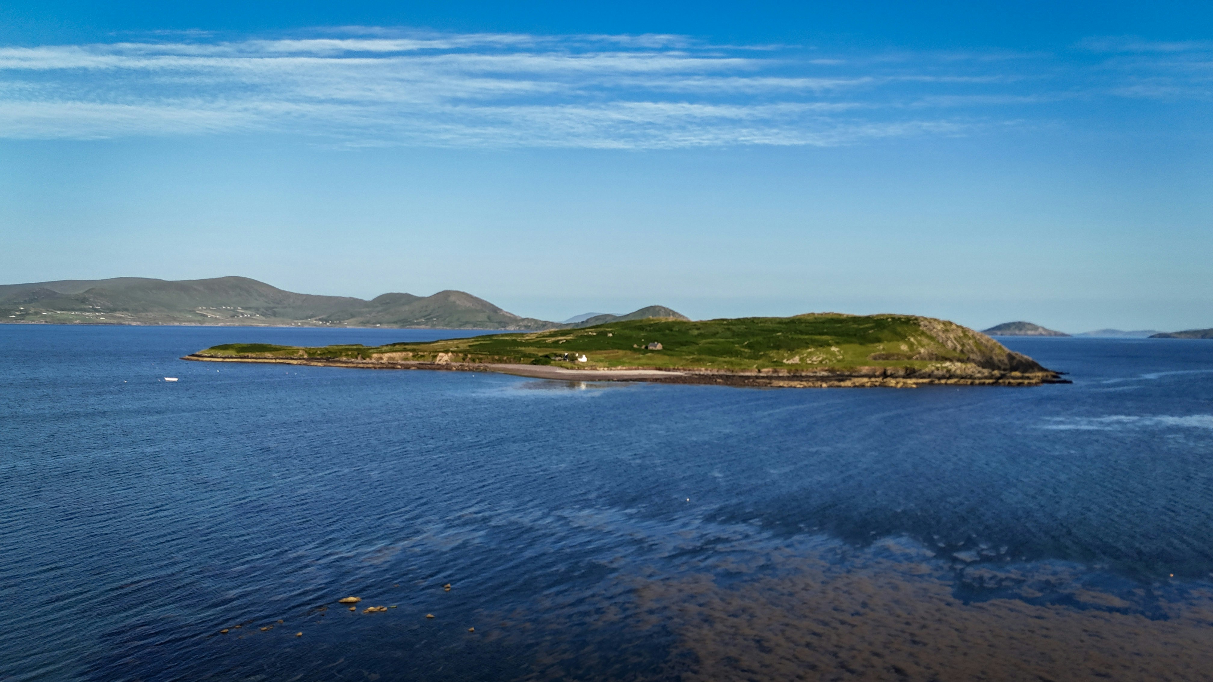 A small island in blue water under a clear sky.