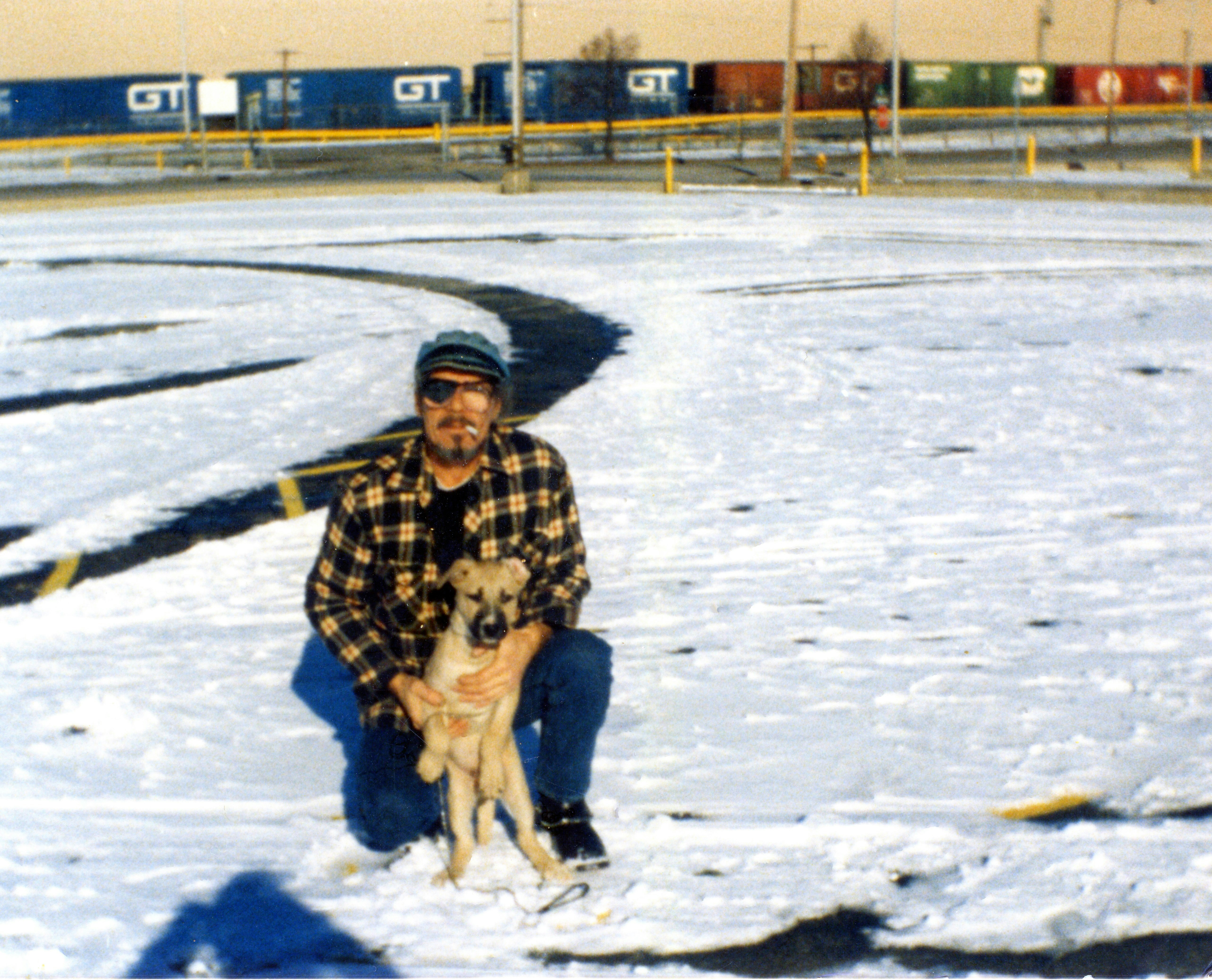 A man and puppy in snow with trains.