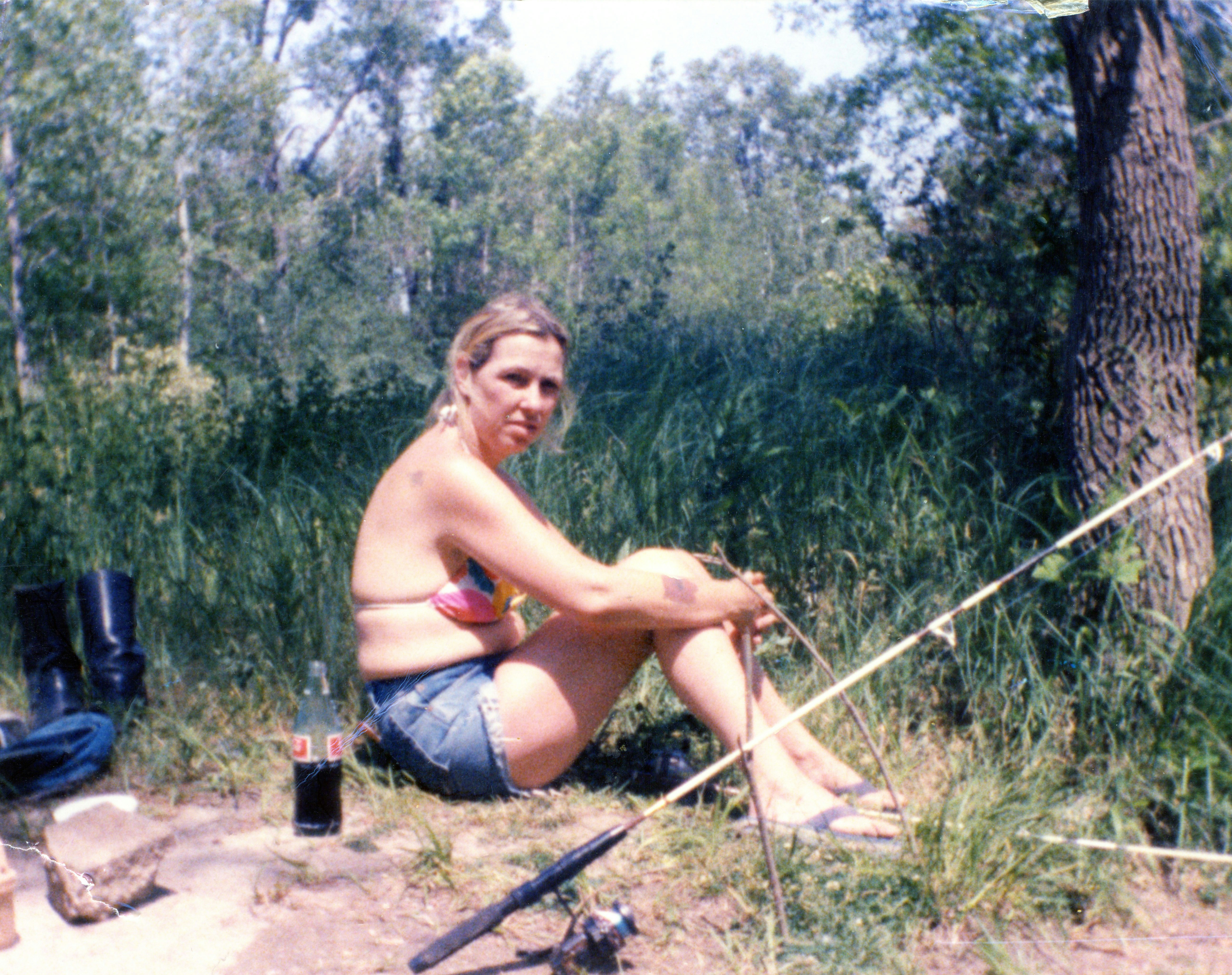 Woman relaxing outdoors with a fishing rod and soda.