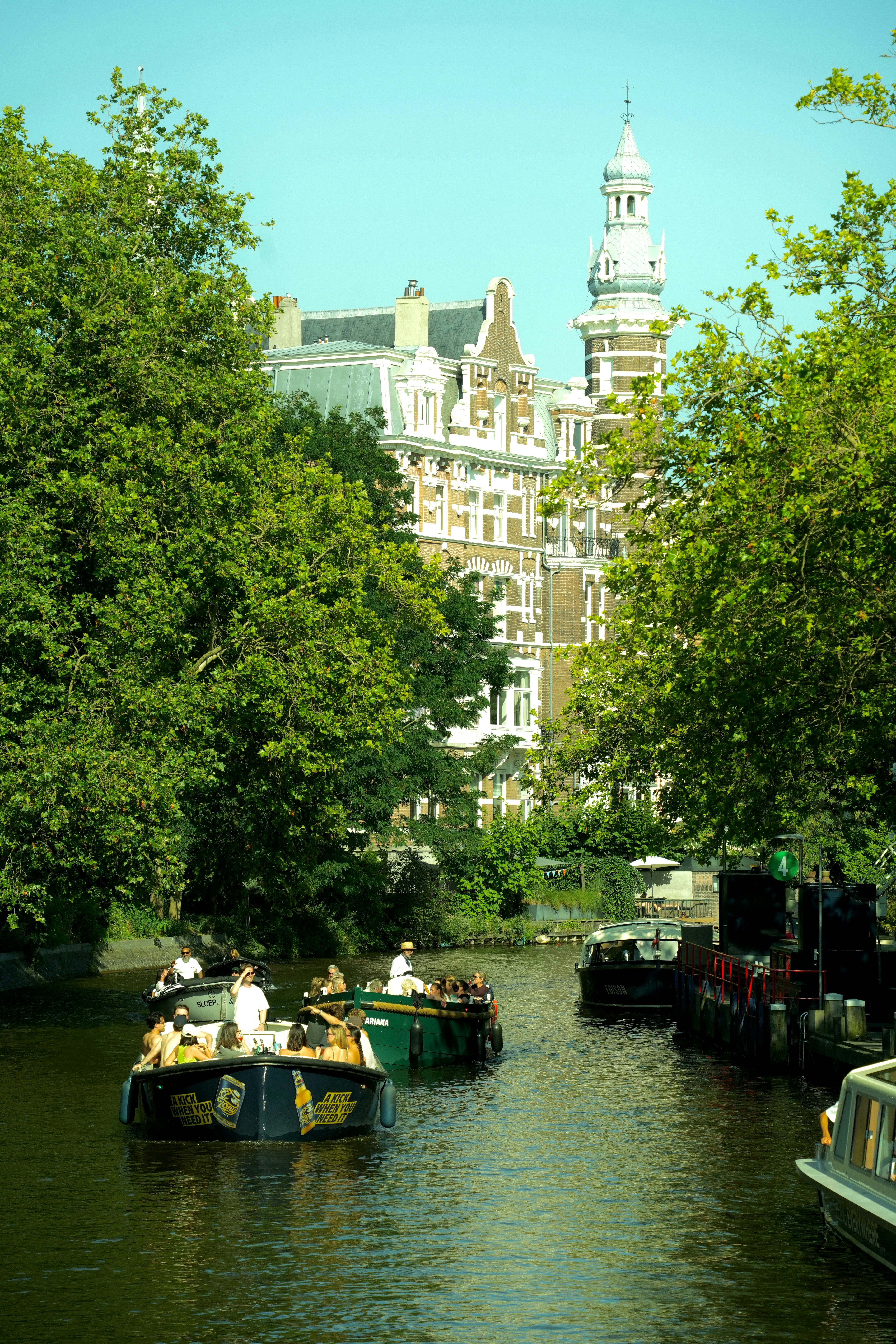 Boats on a canal with historic buildings and green trees