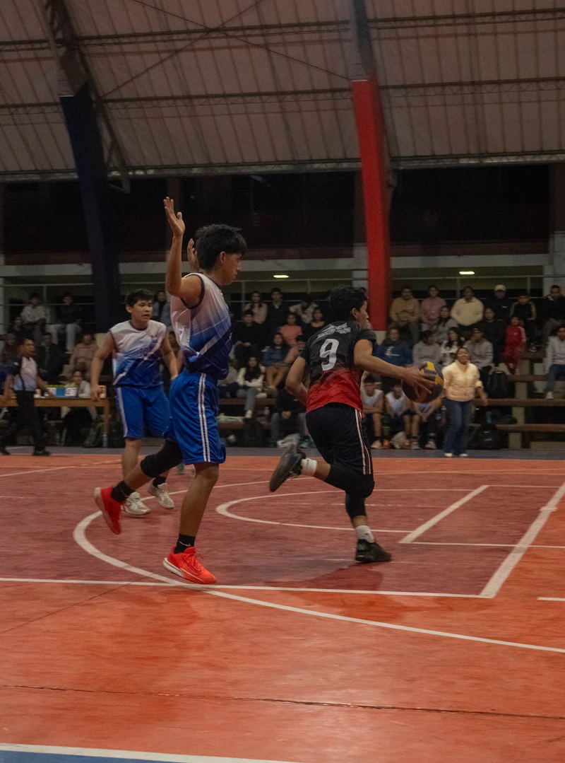Basketball players competing on an indoor court with spectators