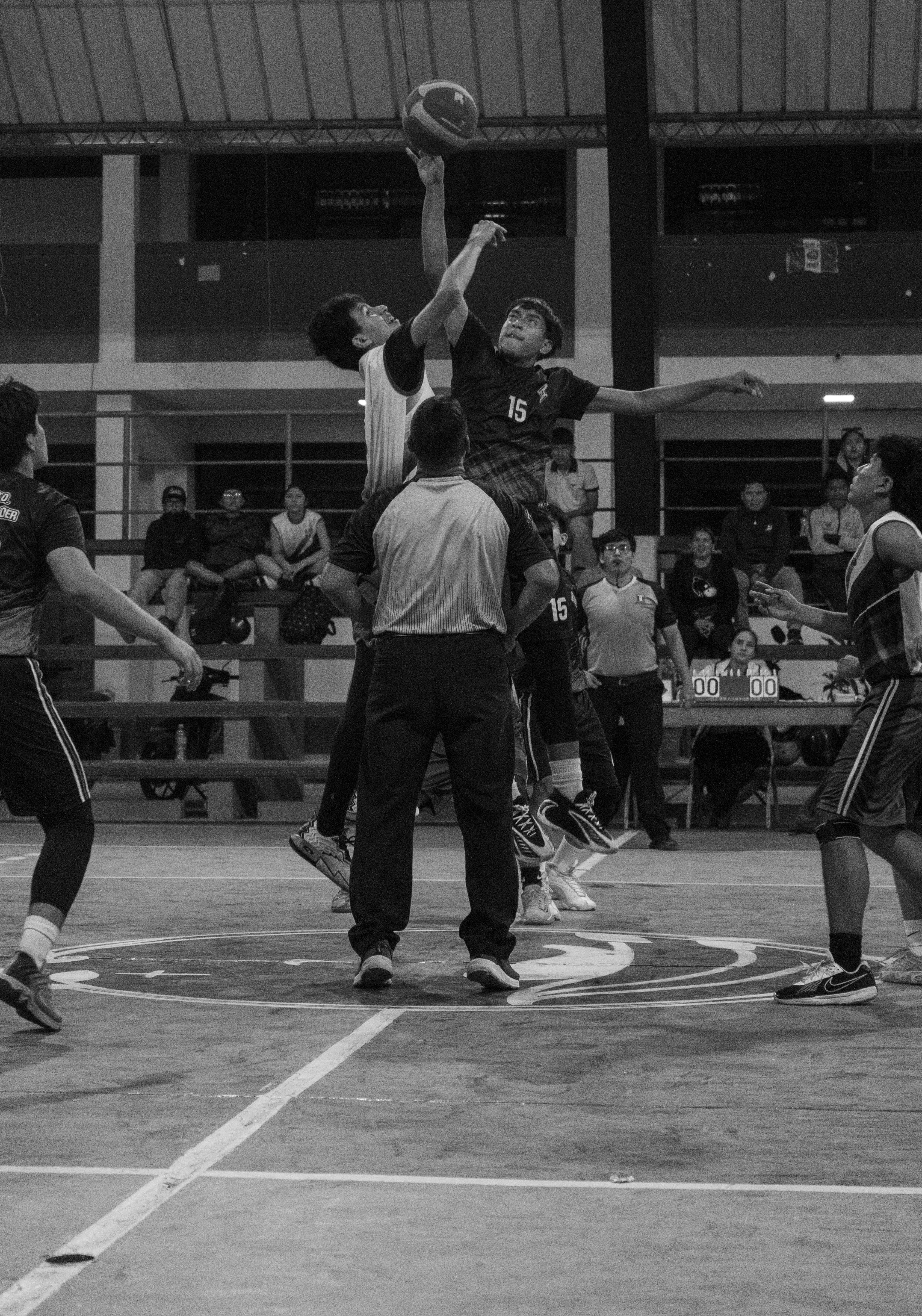 Pemain bola basket melompat untuk mendapatkan tip off dengan wasit.