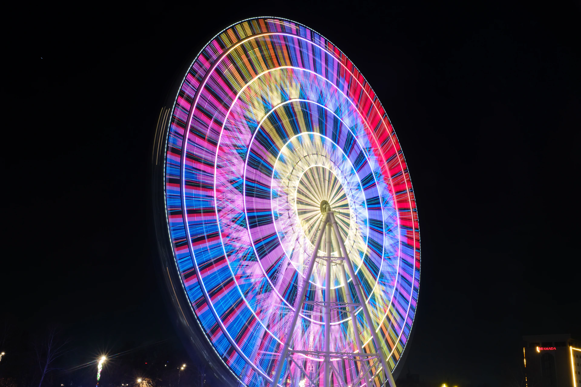 A colorful ferris wheel illuminated at night with light trails