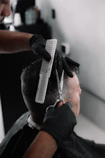 A barber in black gloves cutting a man's hair