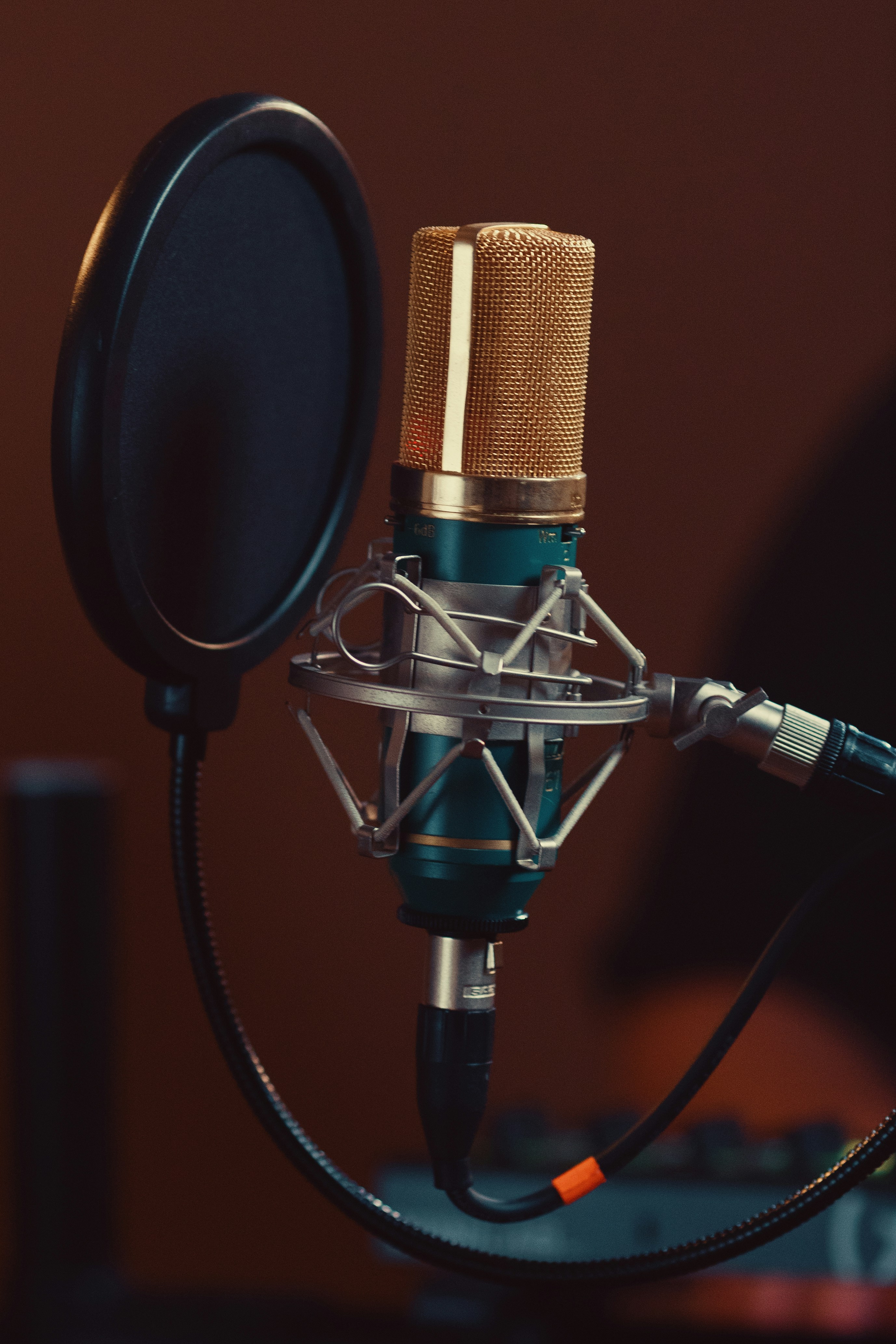 Un micro de studio doré et sarcelle avec un filtre à pop