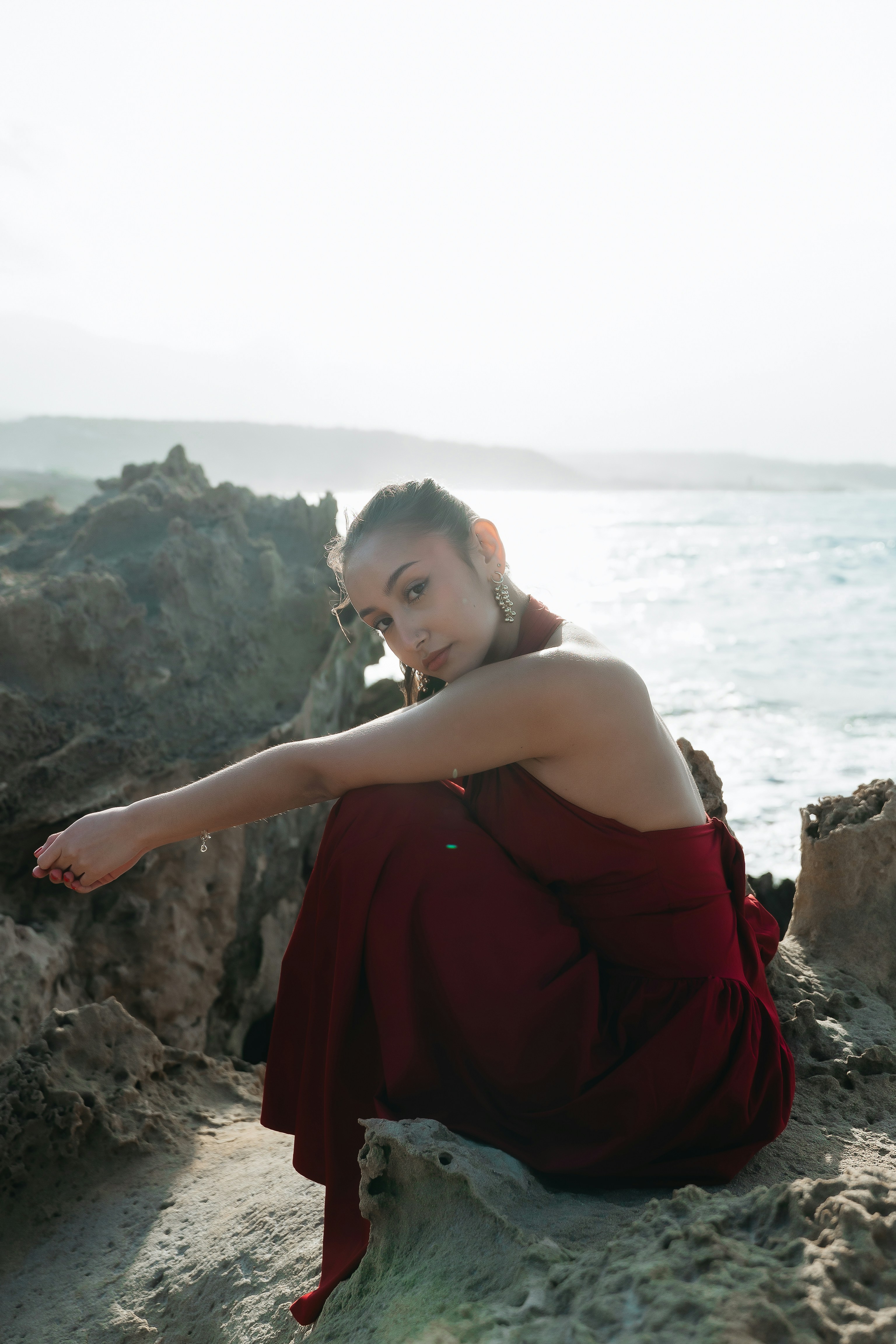 Woman in red dress on sandy beach at sunset