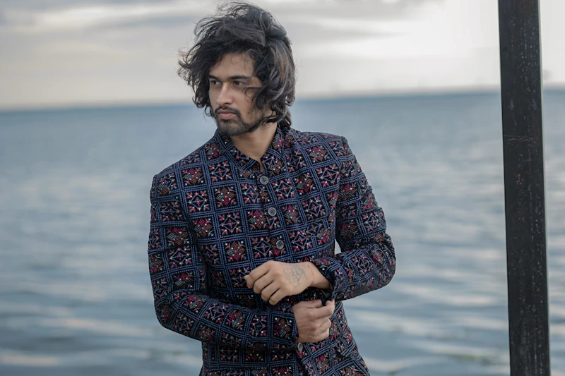 stylish younger man in a patterned jacket by the sea