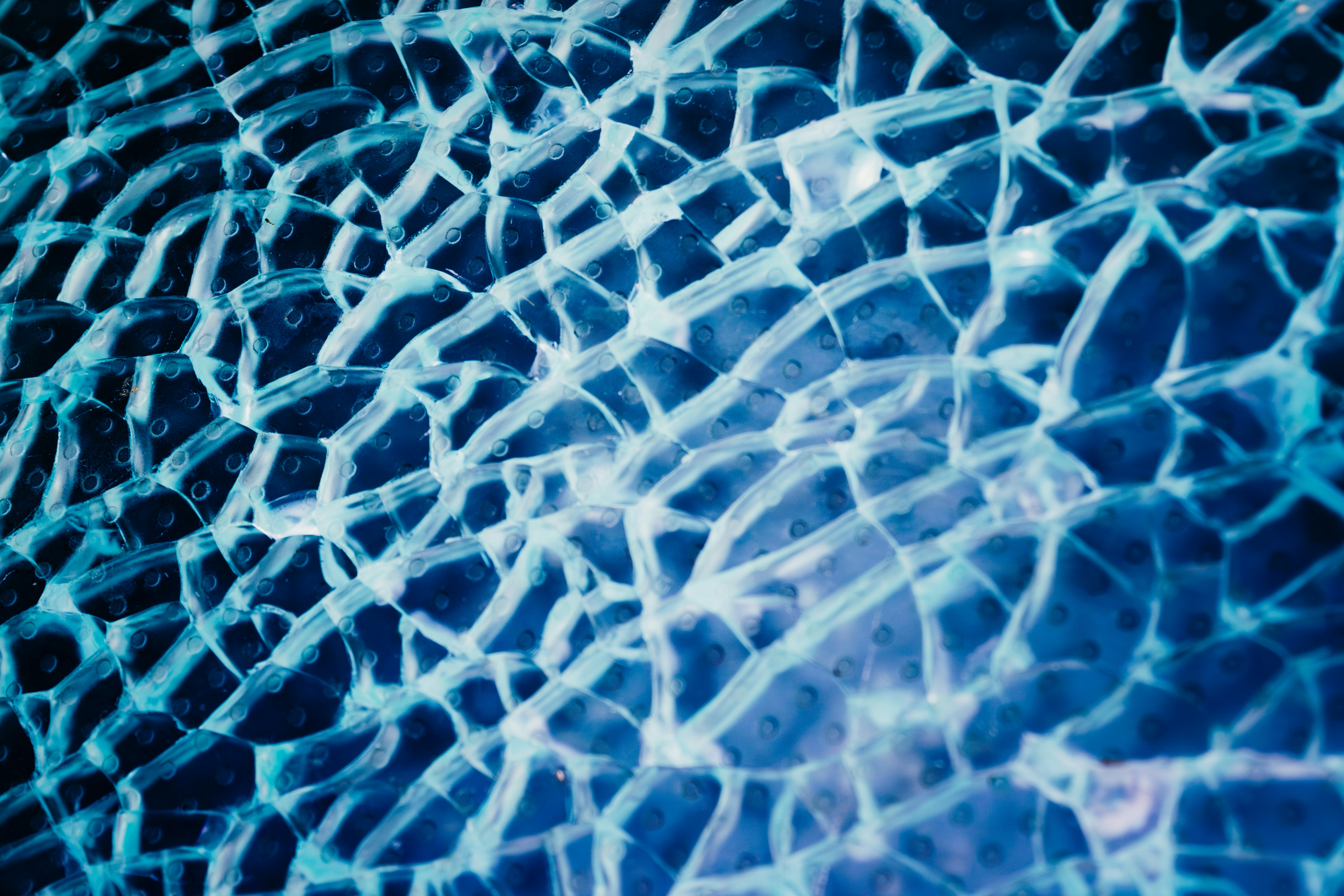 Shattered glass with intricate cracks against a blue background.