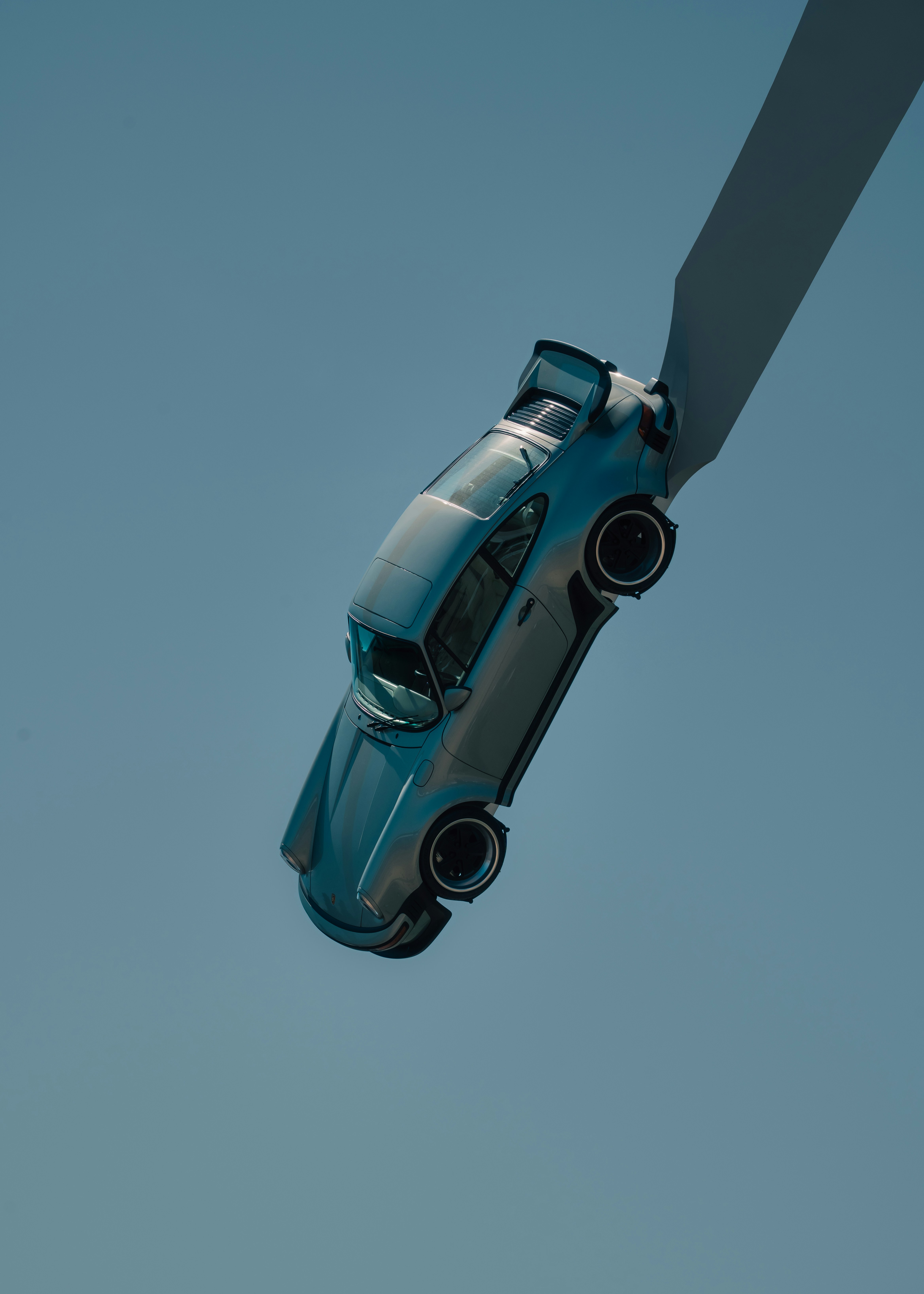 Um carro azul claro suspenso contra um céu azul claro.