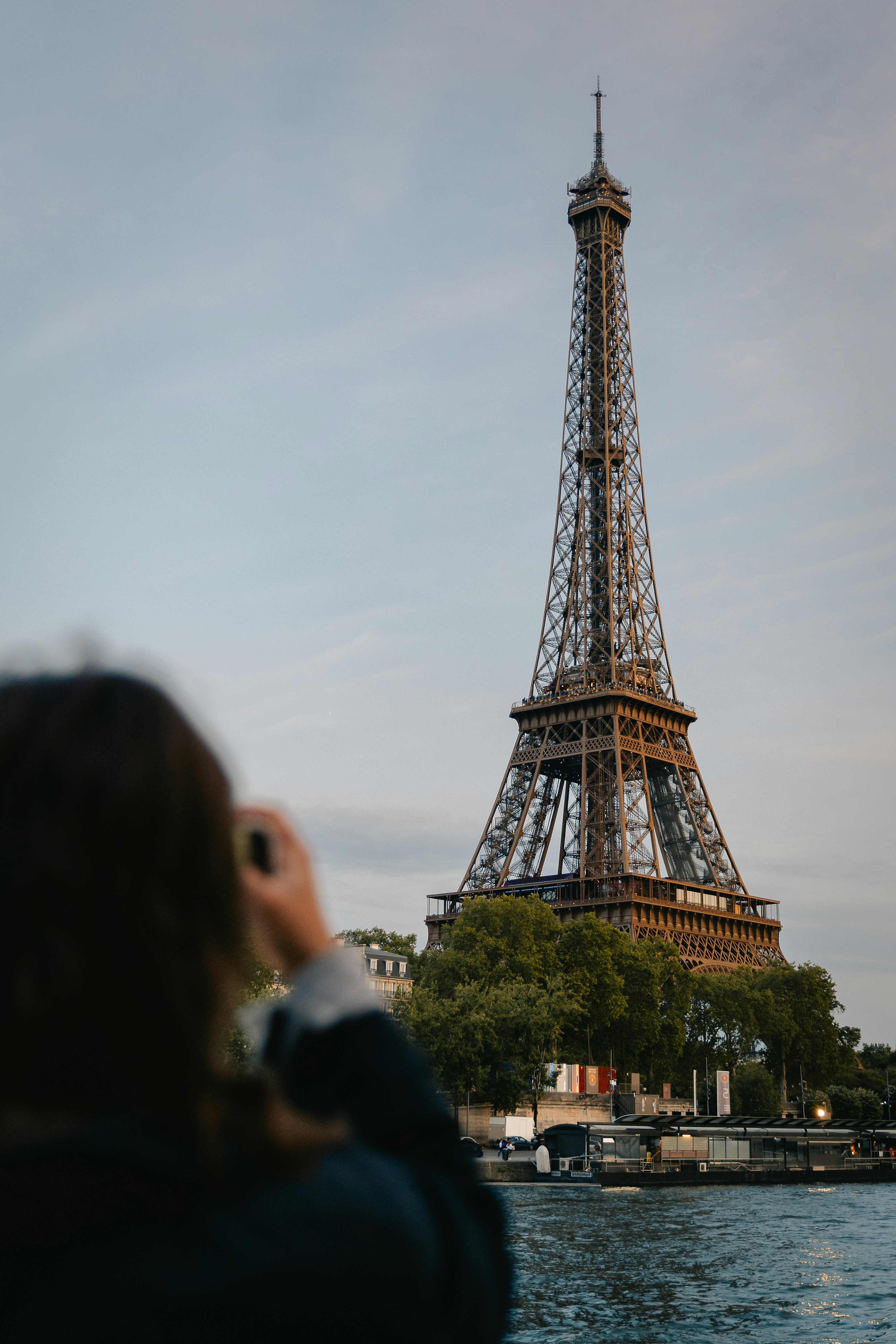 Person photographing eiffel tower from seine river