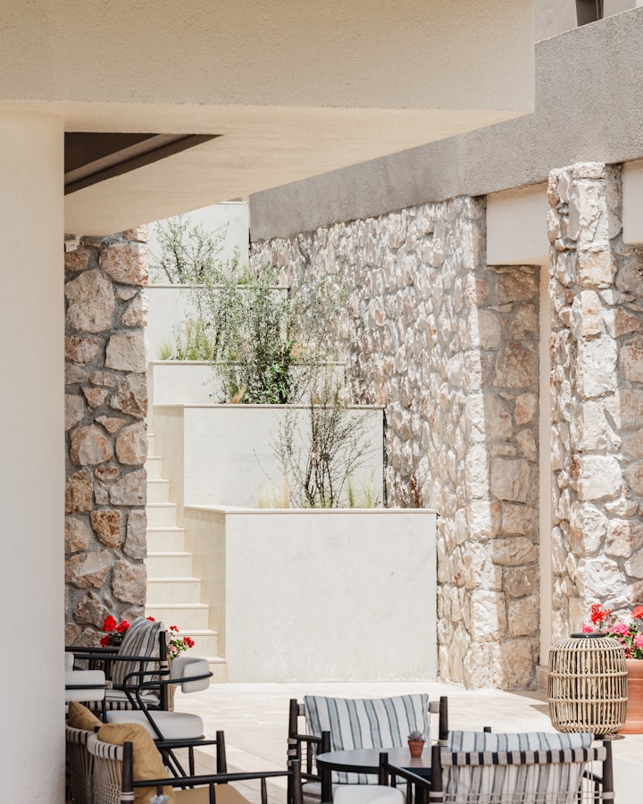 Multi-level stone patio with modern outdoor seating, integrated steps, and warm evening lighting
