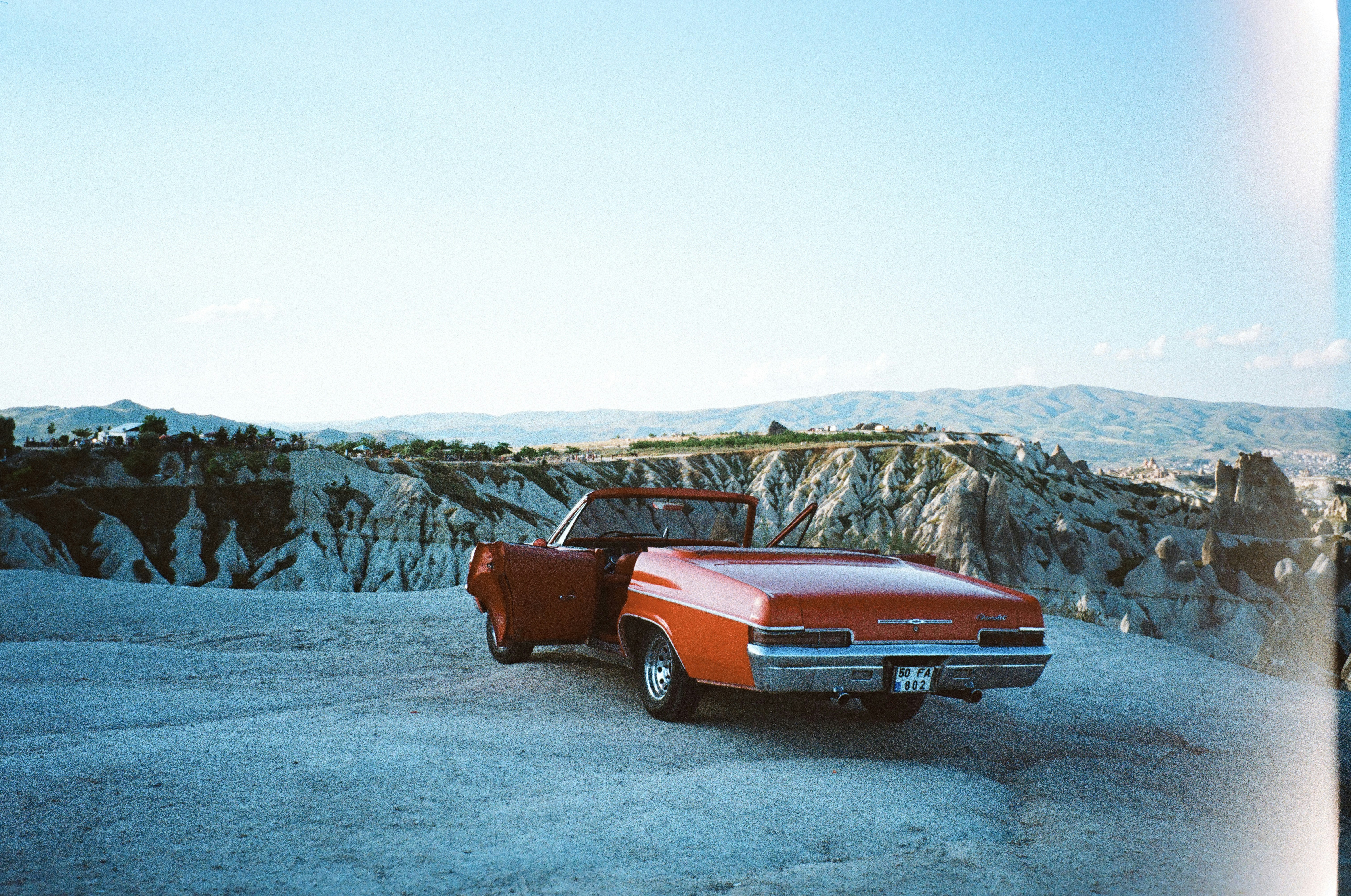 A red convertible car parked on a rocky plateau in Cappadocia, Turkey