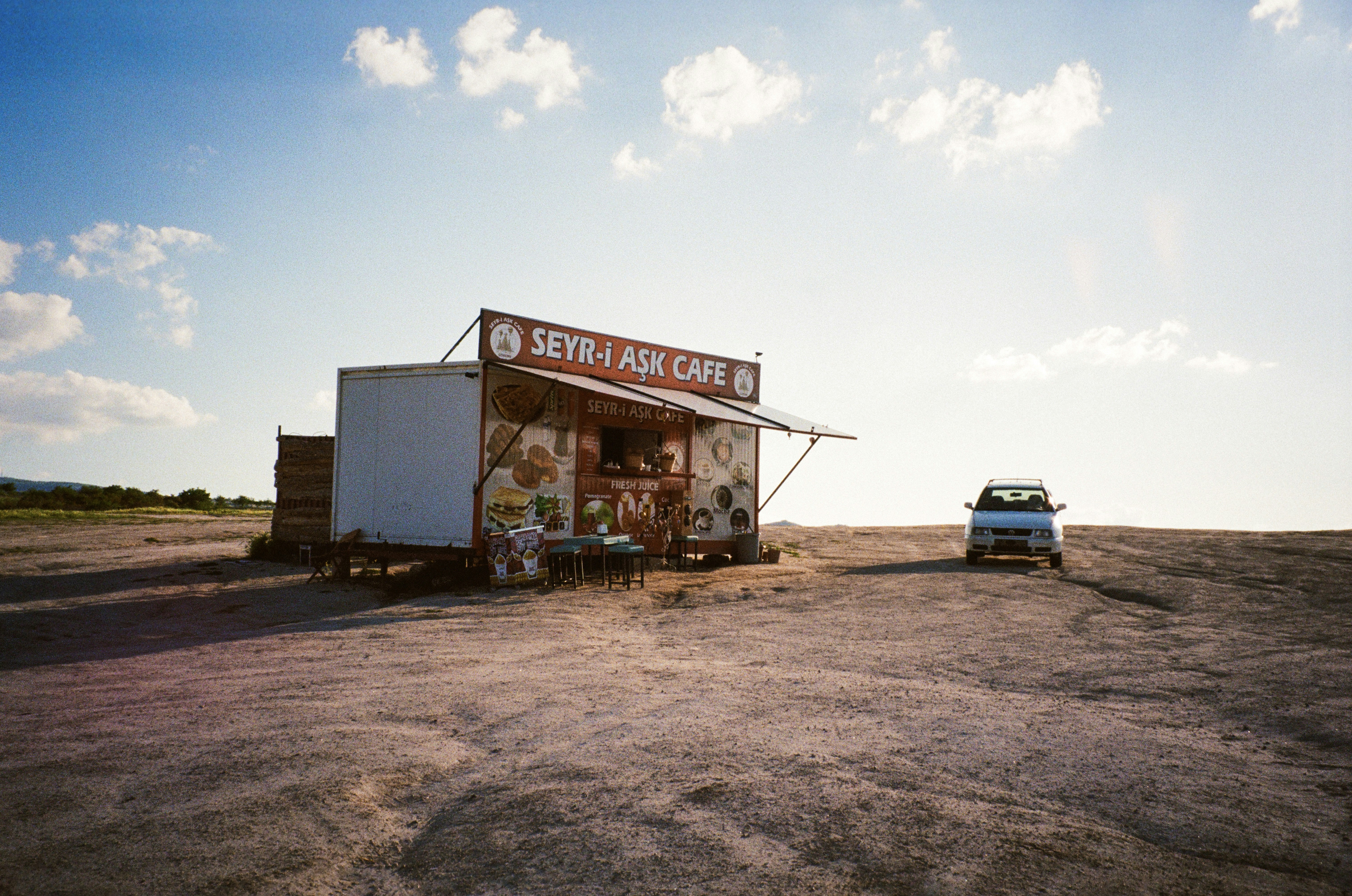 A food trailer cafe with a sign reading "SEYR-i AŞK CAFE" on a rocky landscape