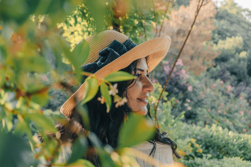 woman in straw hat framed by green leaves
