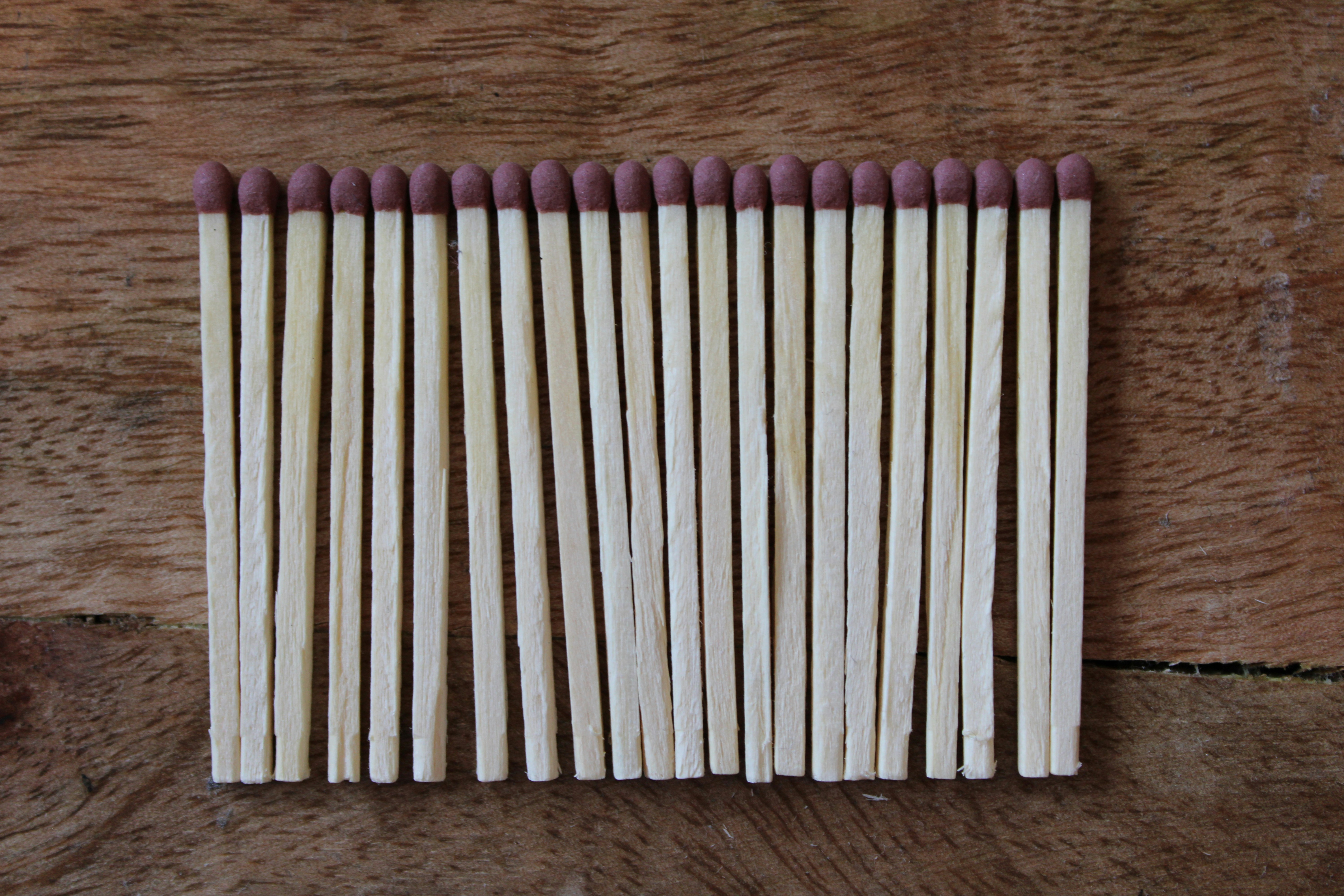 Rows of matches with reddish-brown tips on a wooden board