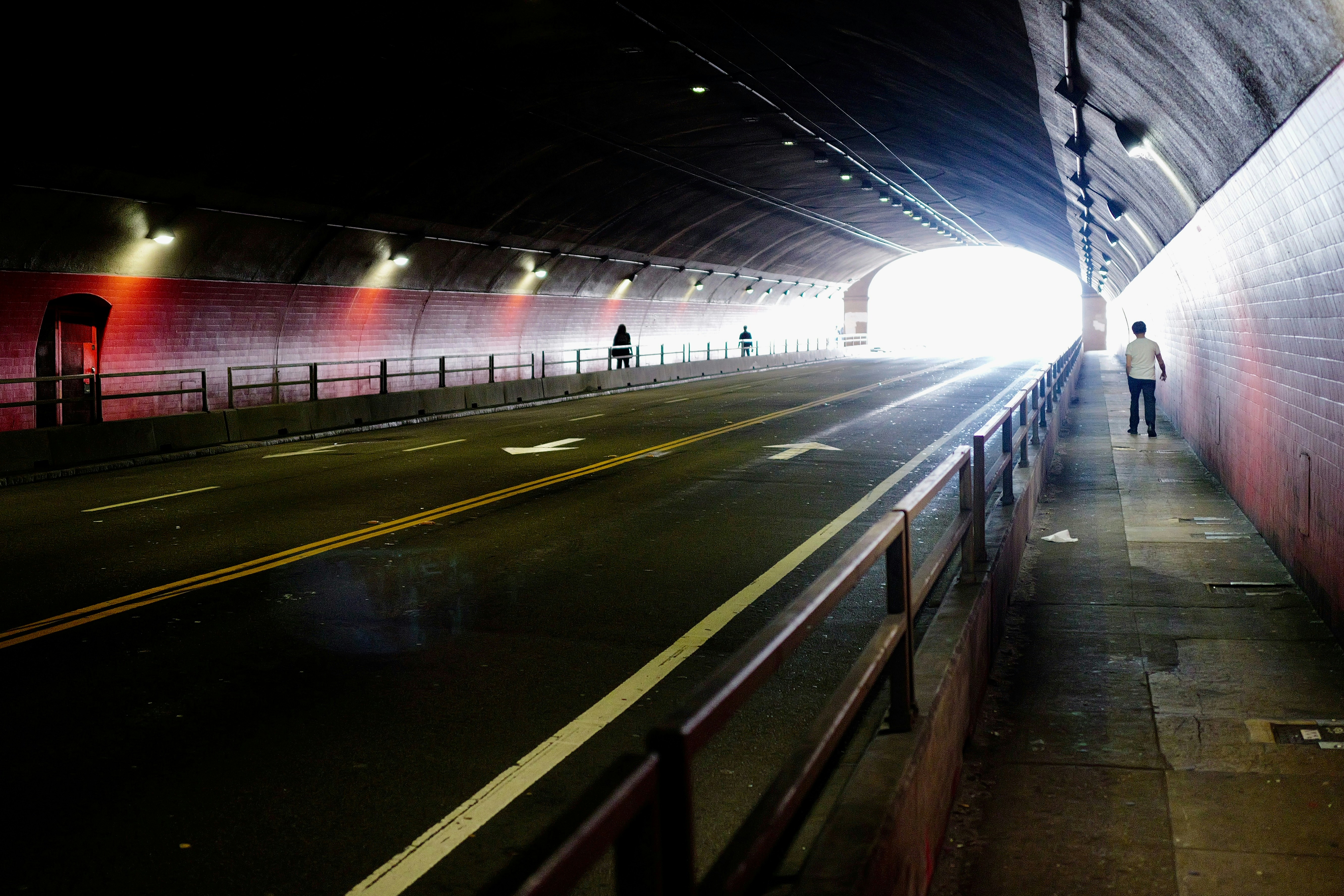 People walking and cycling towards light in a dark tunnel