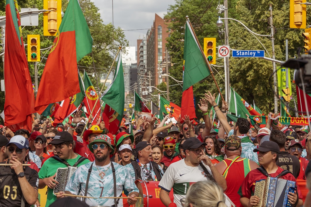 Lively street parade with people waving portuguese flags.