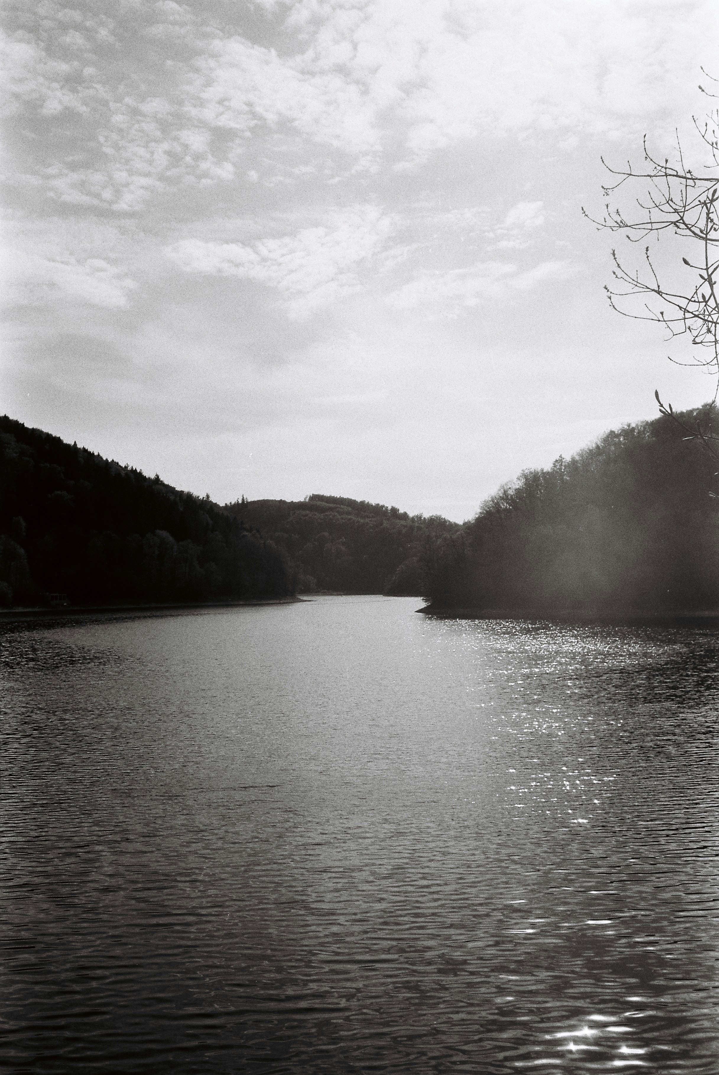 Serene black and white lake surrounded by forested hills
