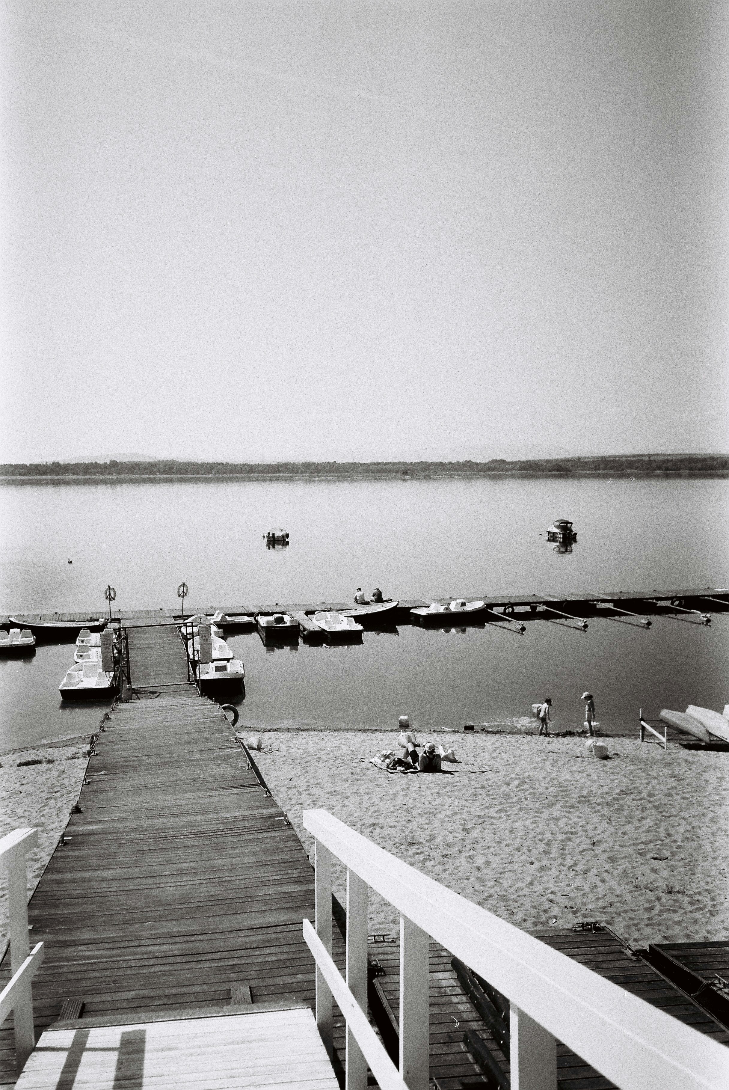 Wooden dock, beach, and boats on a calm lake