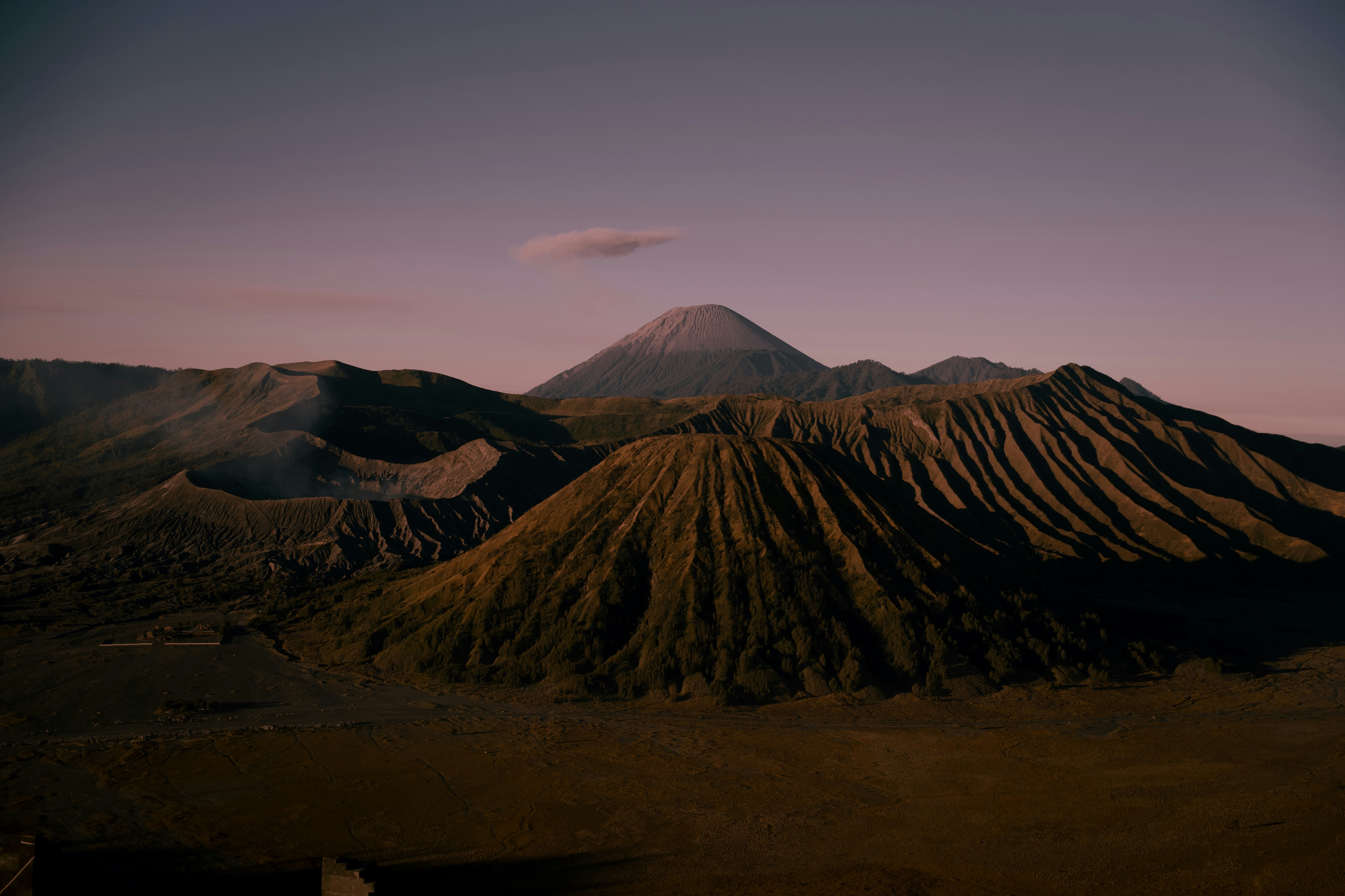 Multiple volcanic peaks under a purple sky at dawn.