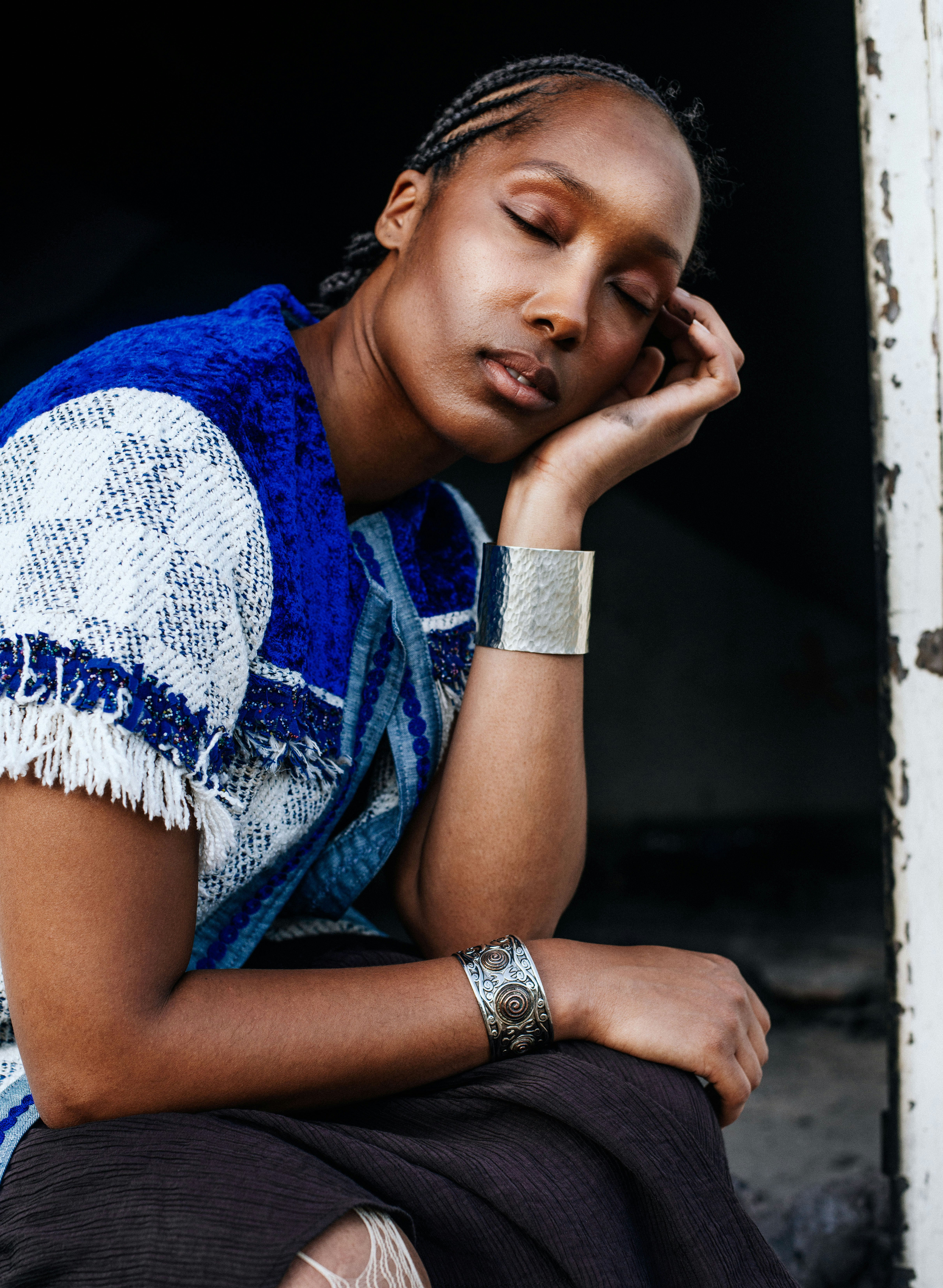Woman with braided hair, silver cuffs, eyes closed