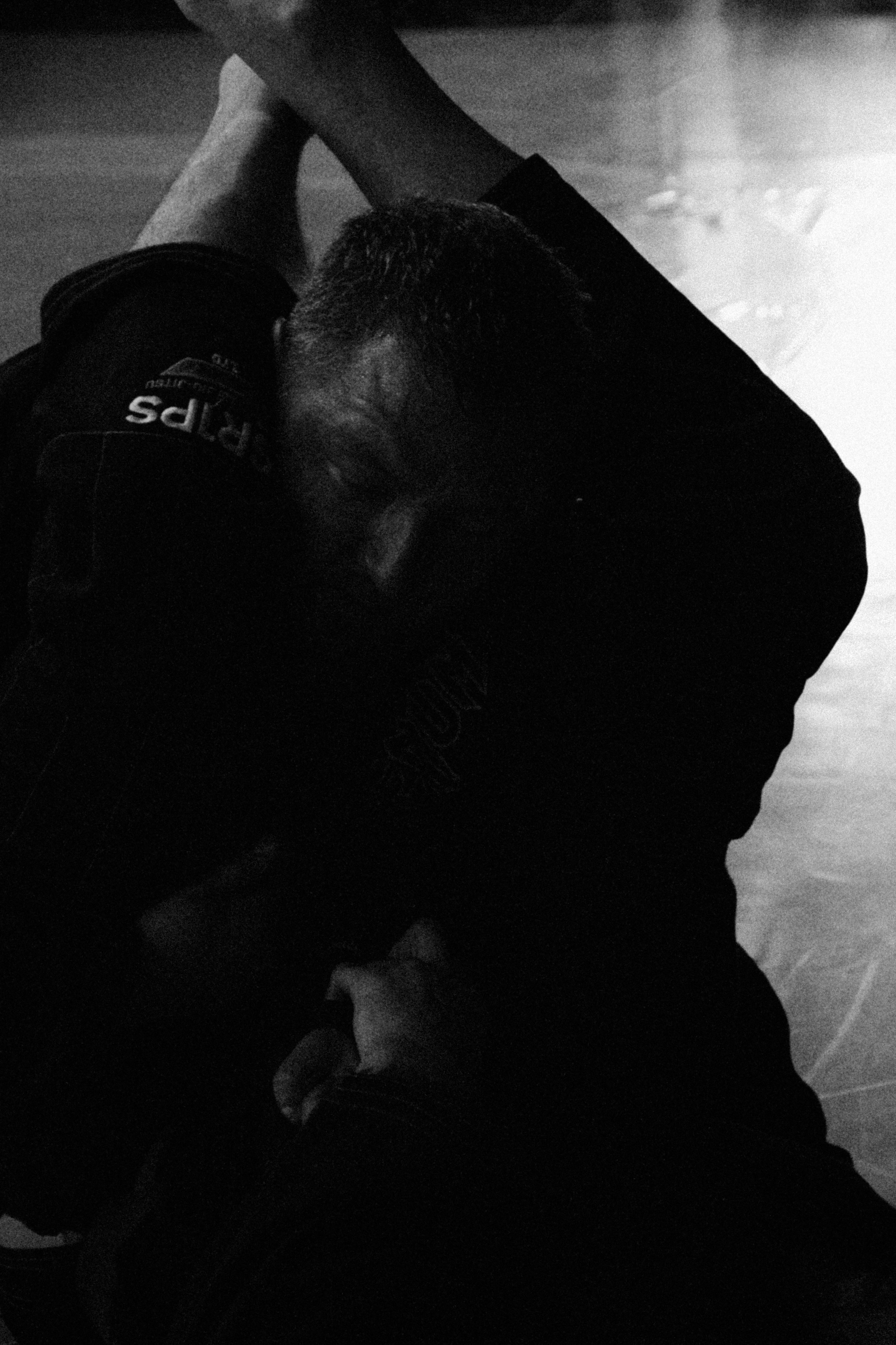 Two people grappling in a dark, high-contrast martial arts scene