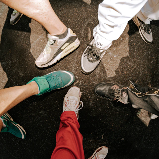 Many feet in different shoes gathered together on dark pavement