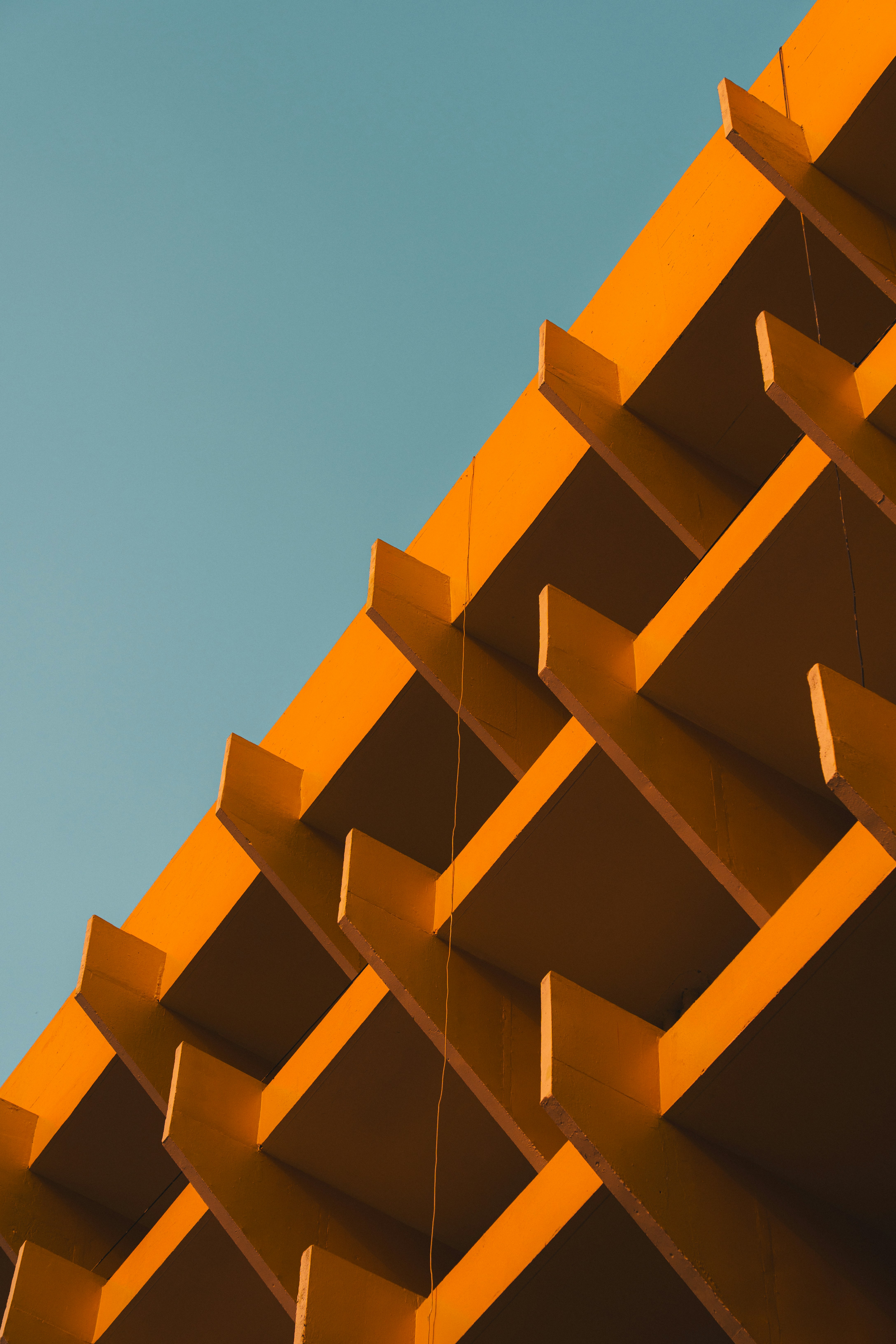 Orange geometric building facade against a clear blue sky