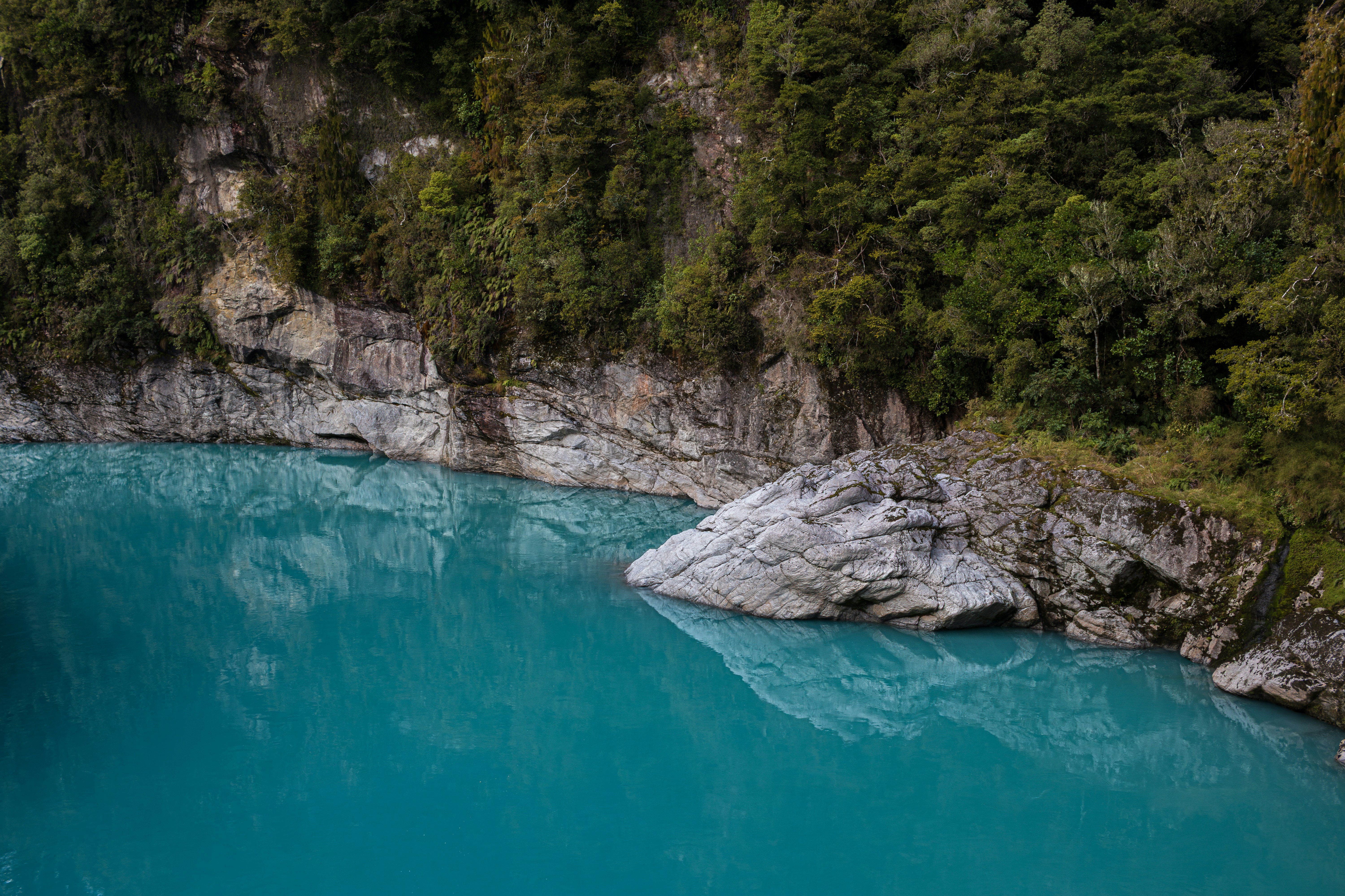 Vibrant blue lake surrounded by rocky cliffs and green forest