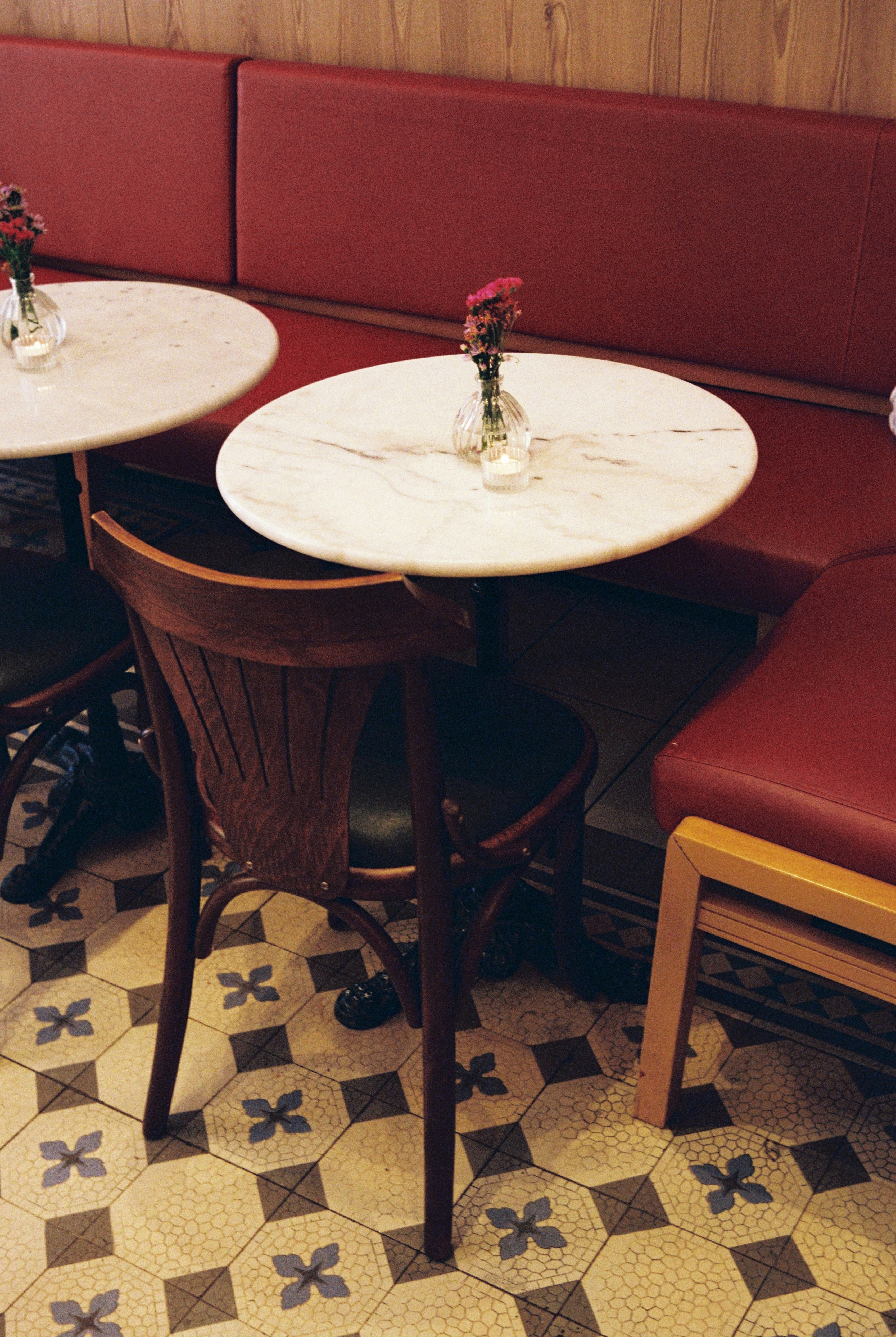 Empty cafe tables with red booths and patterned floor.