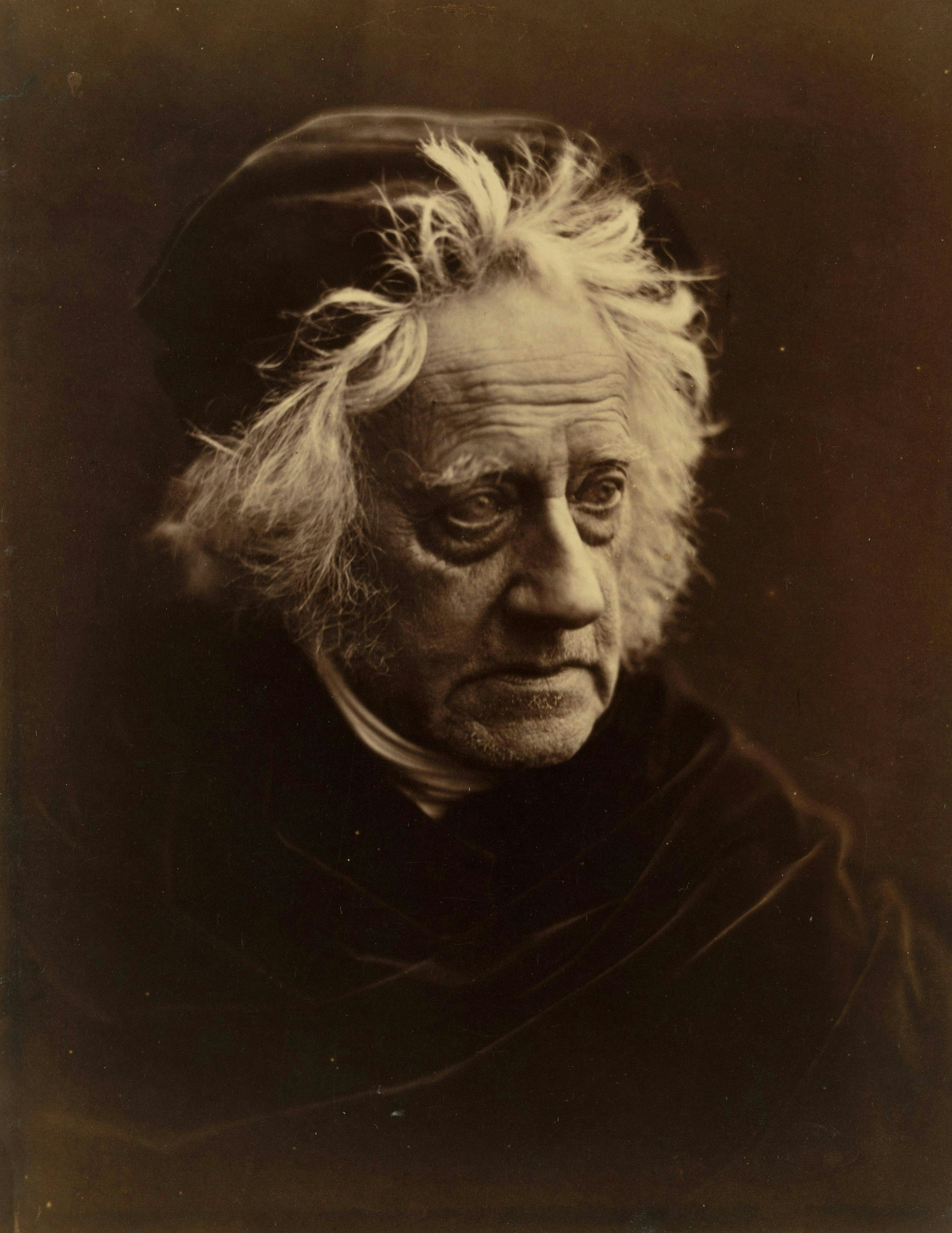 Elderly man with wild white hair and dark cap.
