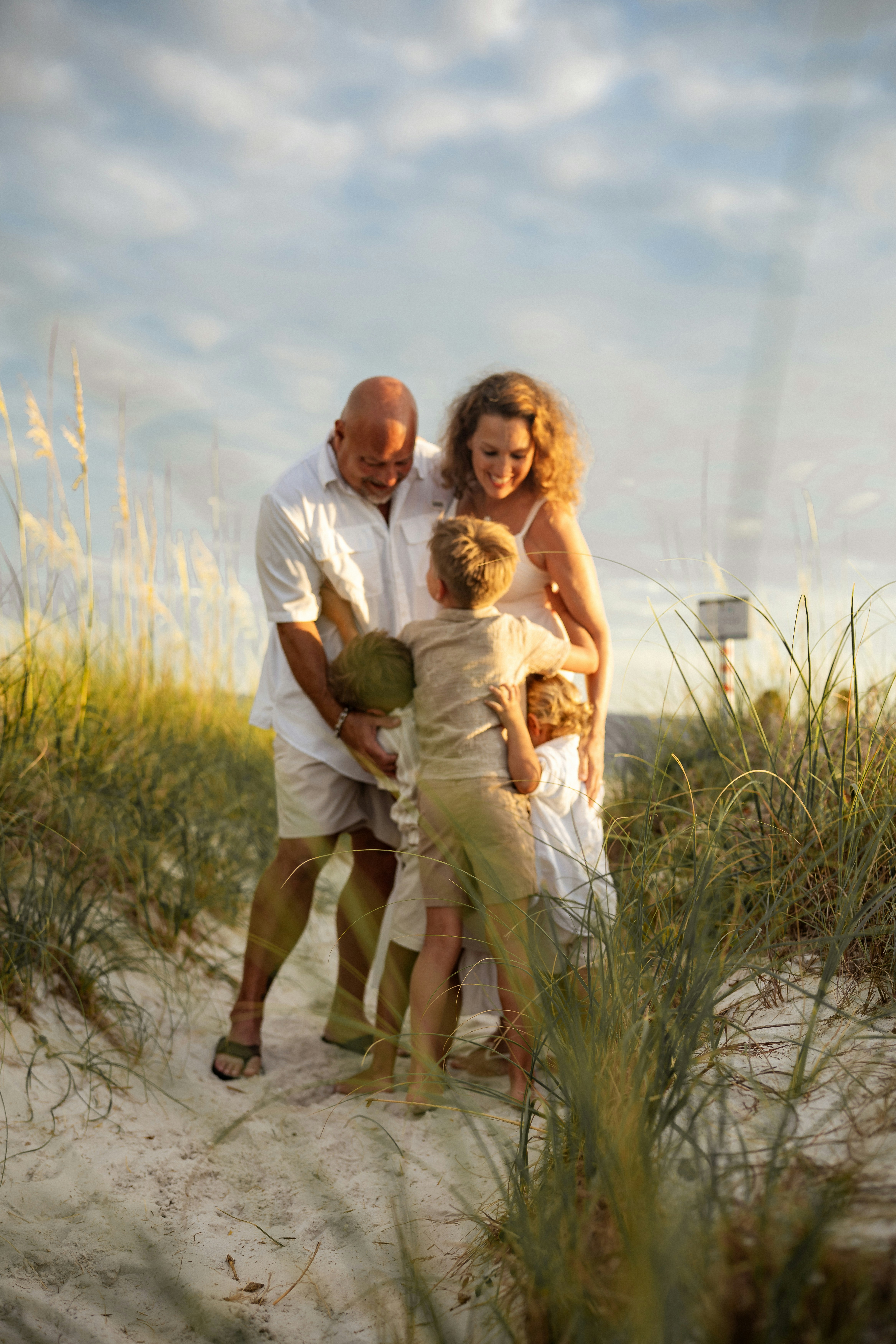 Family holding a coconut on a sandy path.