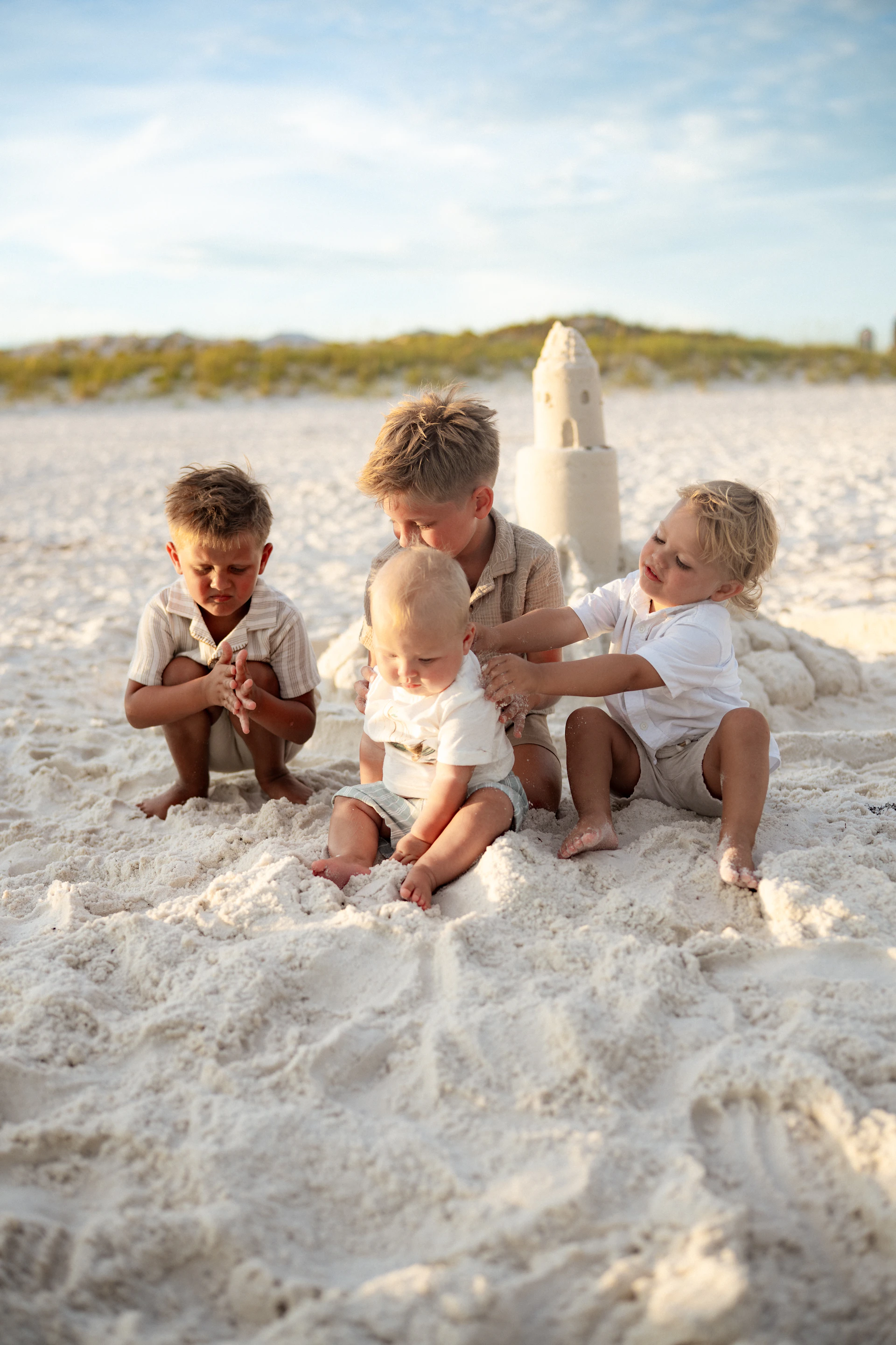 Young boys enjoying a sandcastle on a sunny beach.
