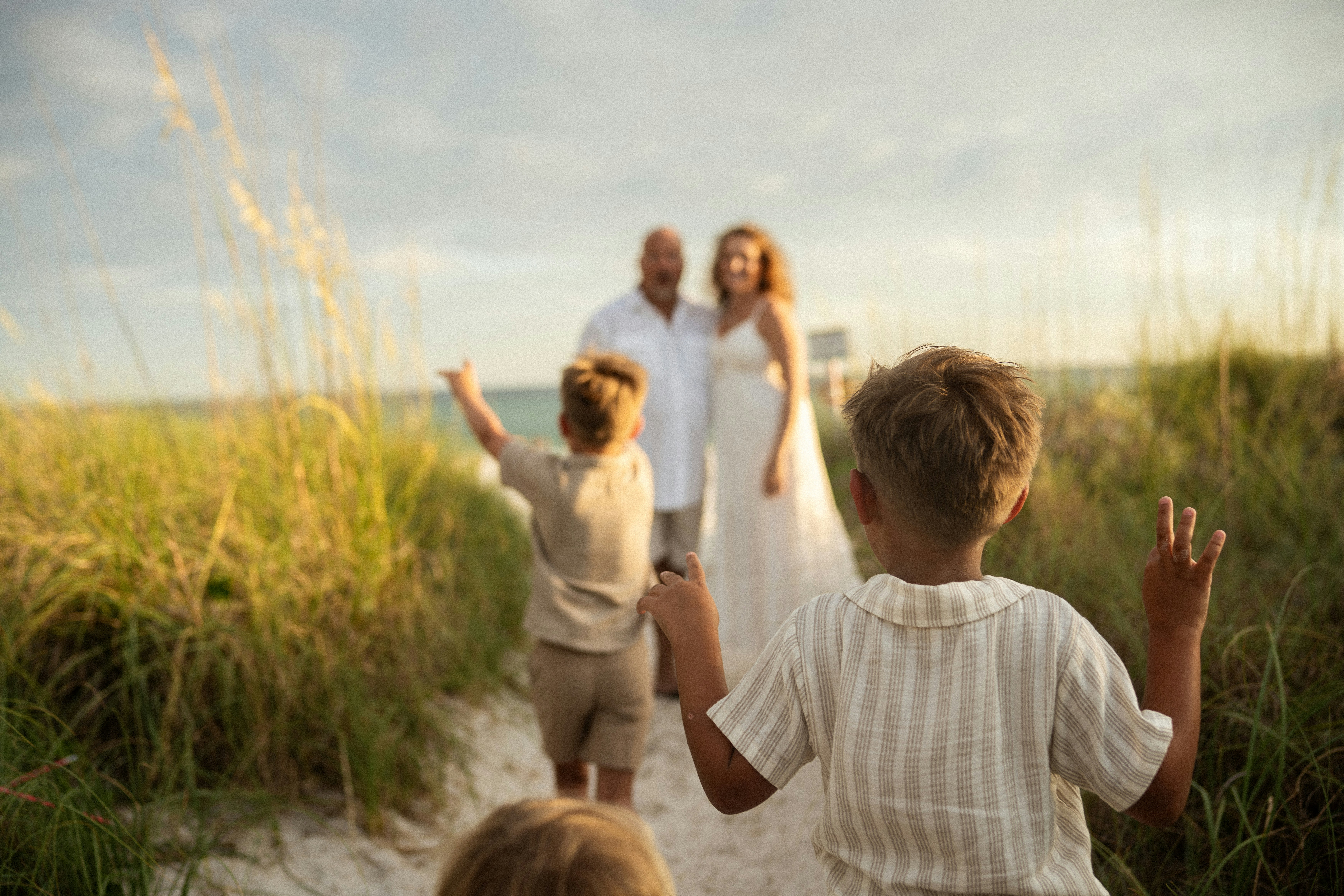 Young boys walk towards a couple on a beach path.