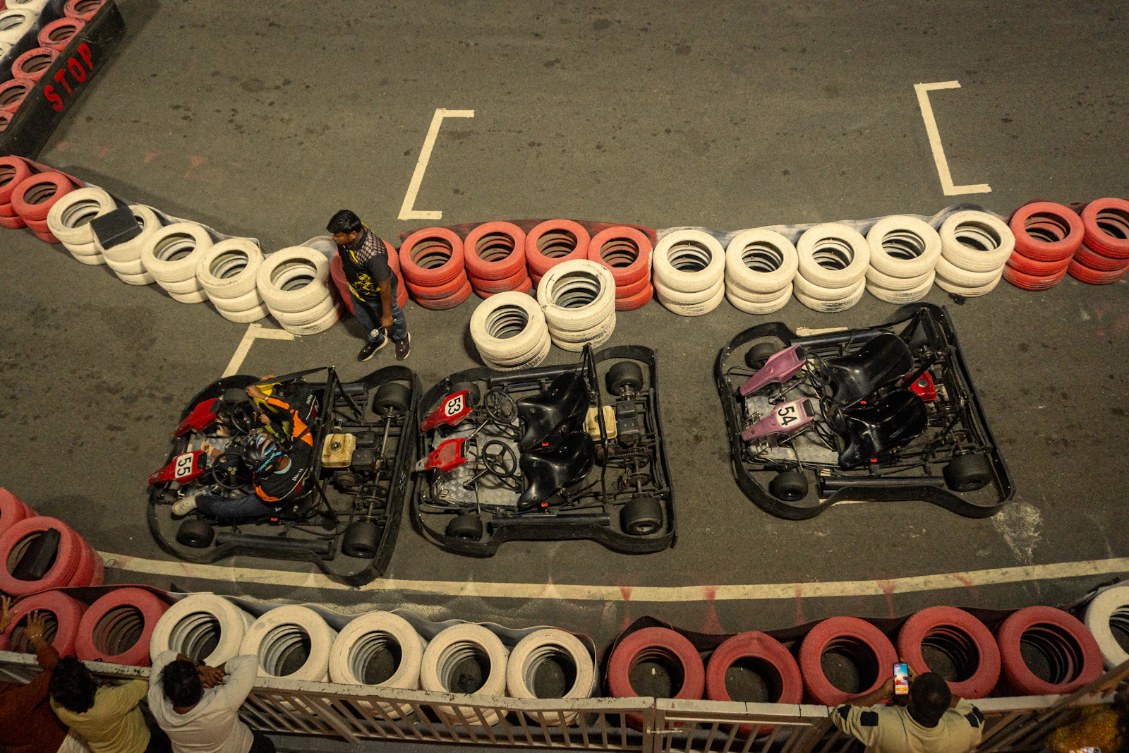 Karts alignés sur une piste de karting indoor bordée de barrières de pneus en Belgique