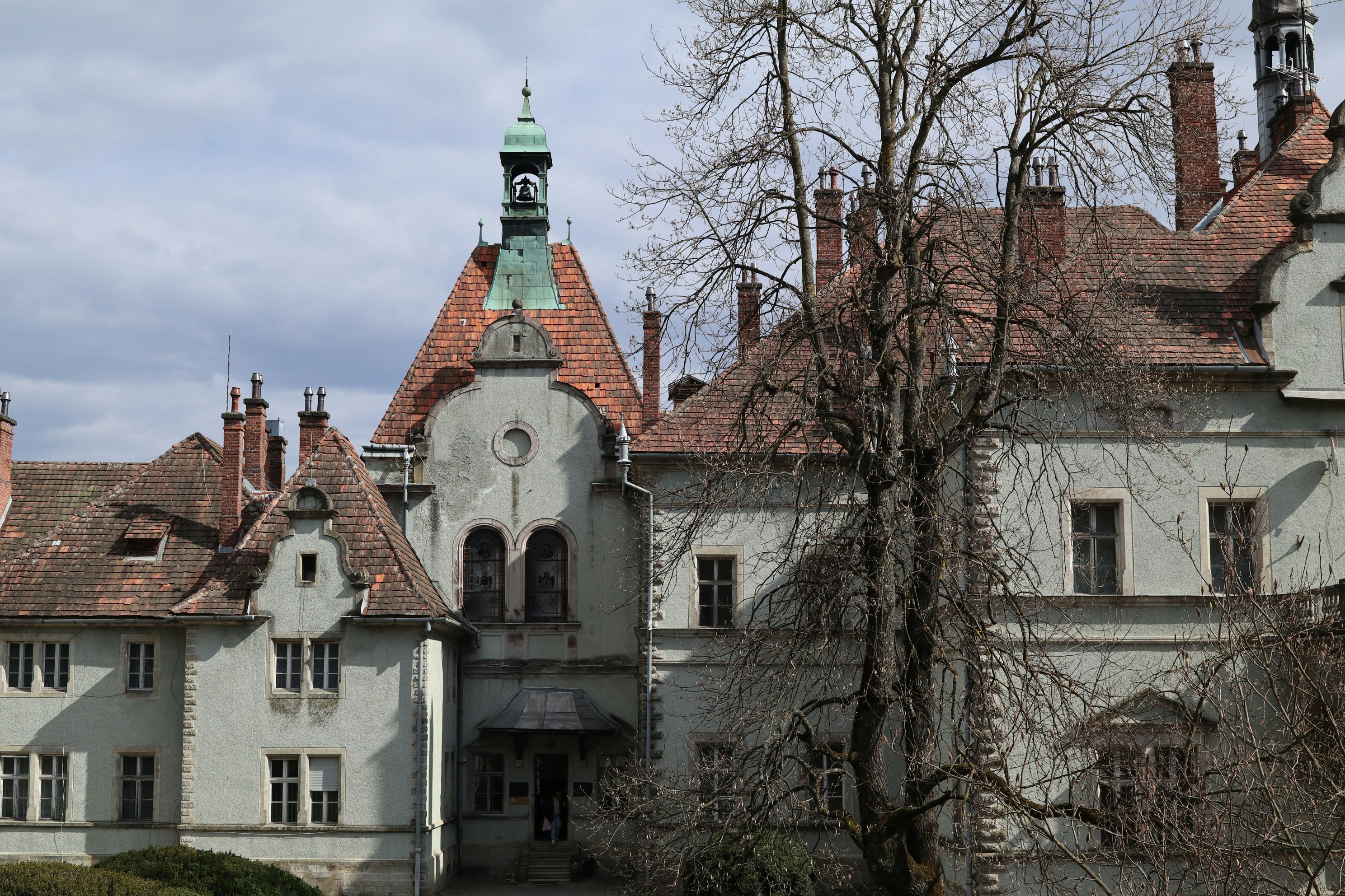 Historic stone castle with multiple roofs and dormant trees