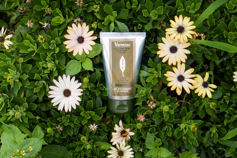 Cosmetic tube nestled among green foliage and white daisy flowers.