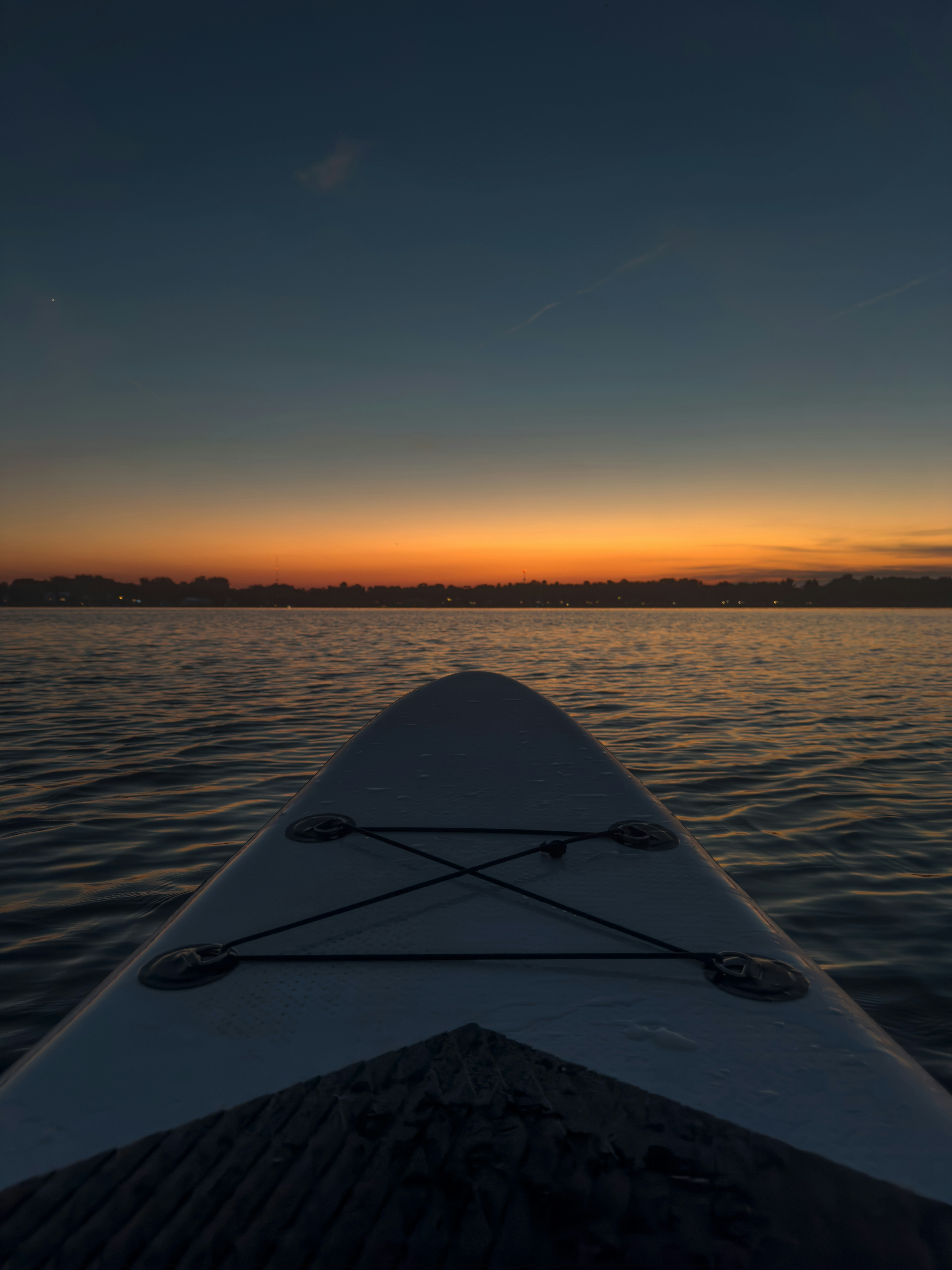 Paddleboard sur une eau calme pendant un coucher de soleil coloré.