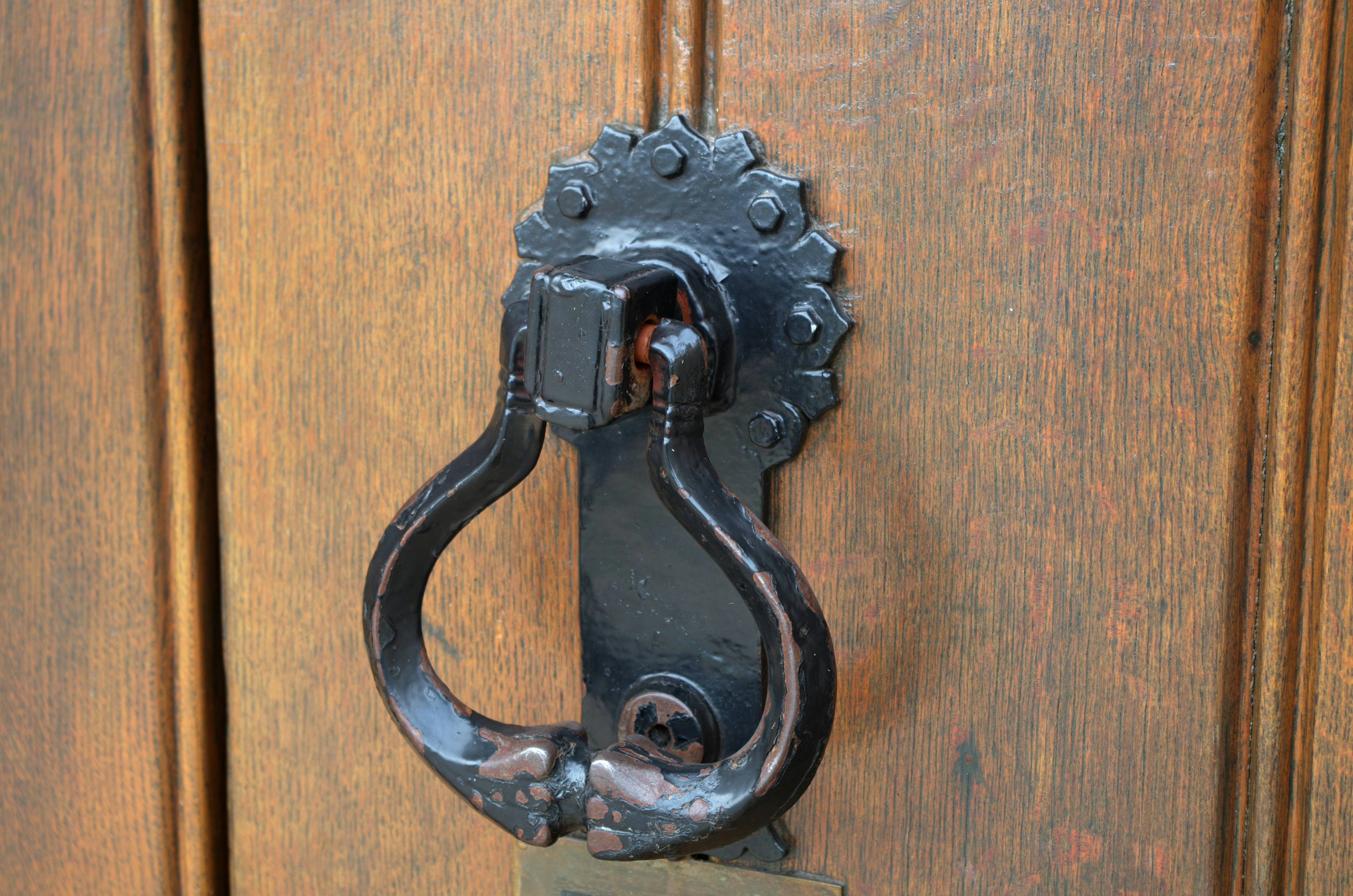 A black metal door knocker on a rustic wooden door