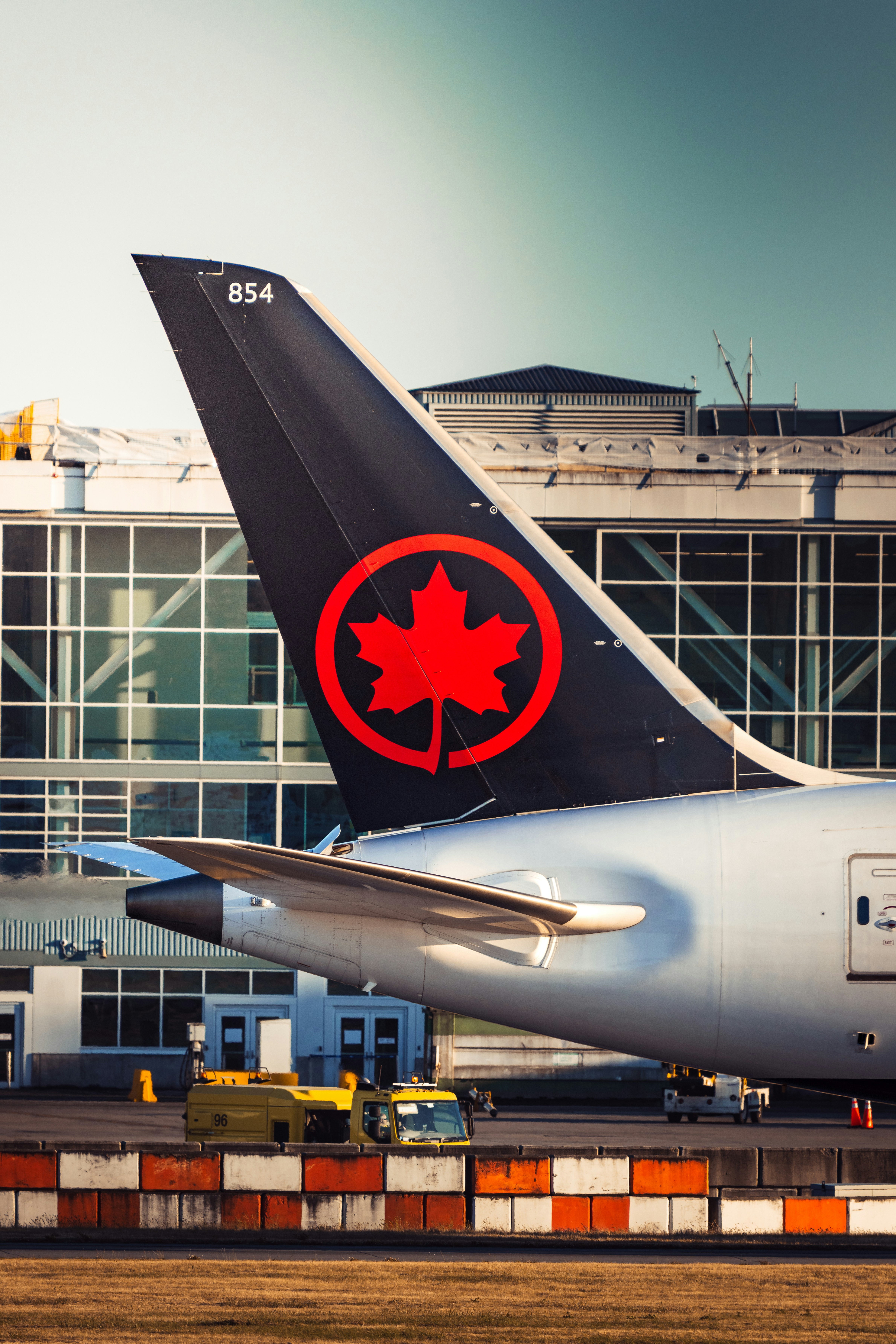 Air canada airplane tail with maple leaf logo at airport.